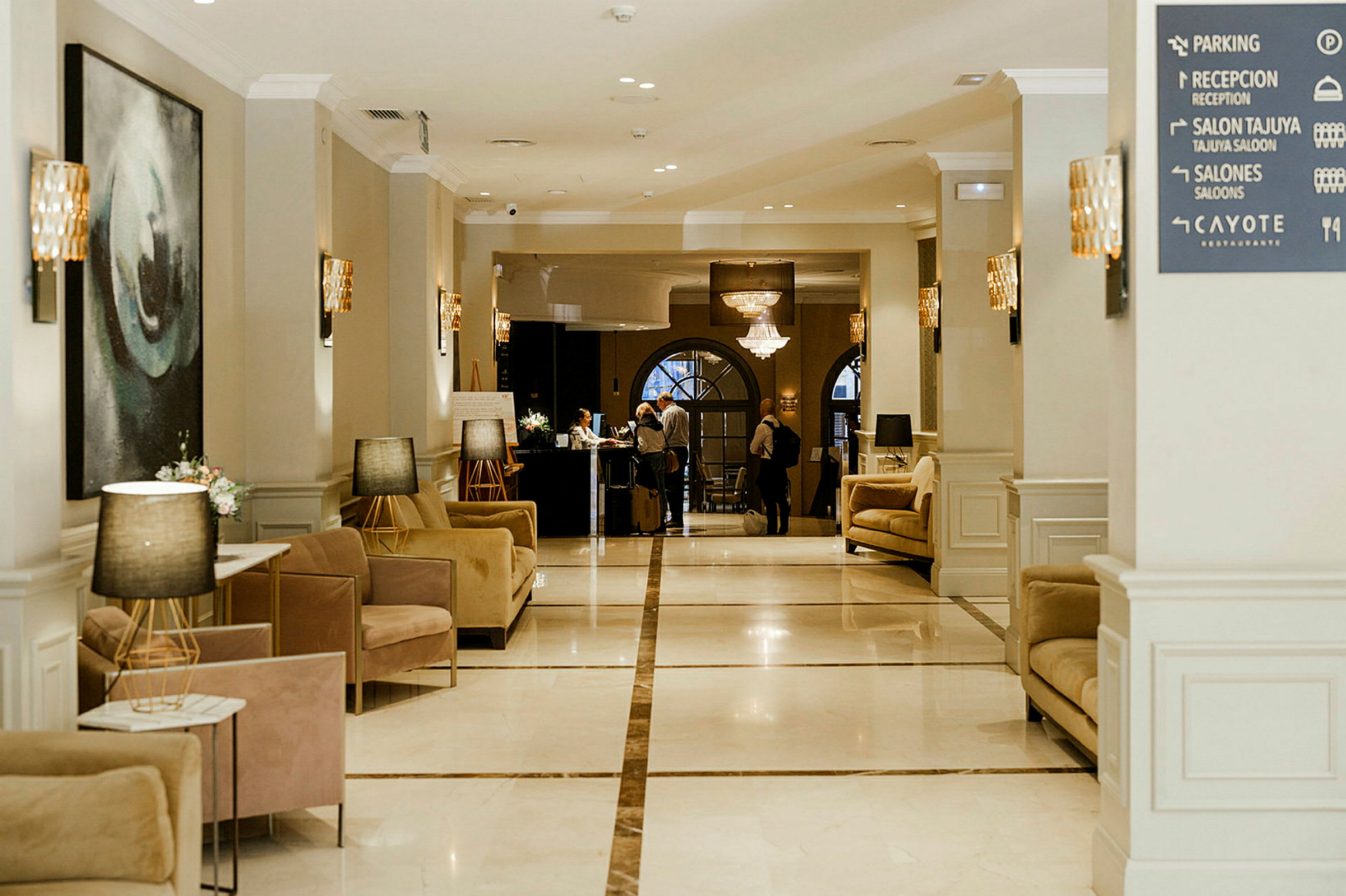 Billedet viser en hotellobby med elegante siddeområder og en reception i baggrunden. (AI-genereret tekst)