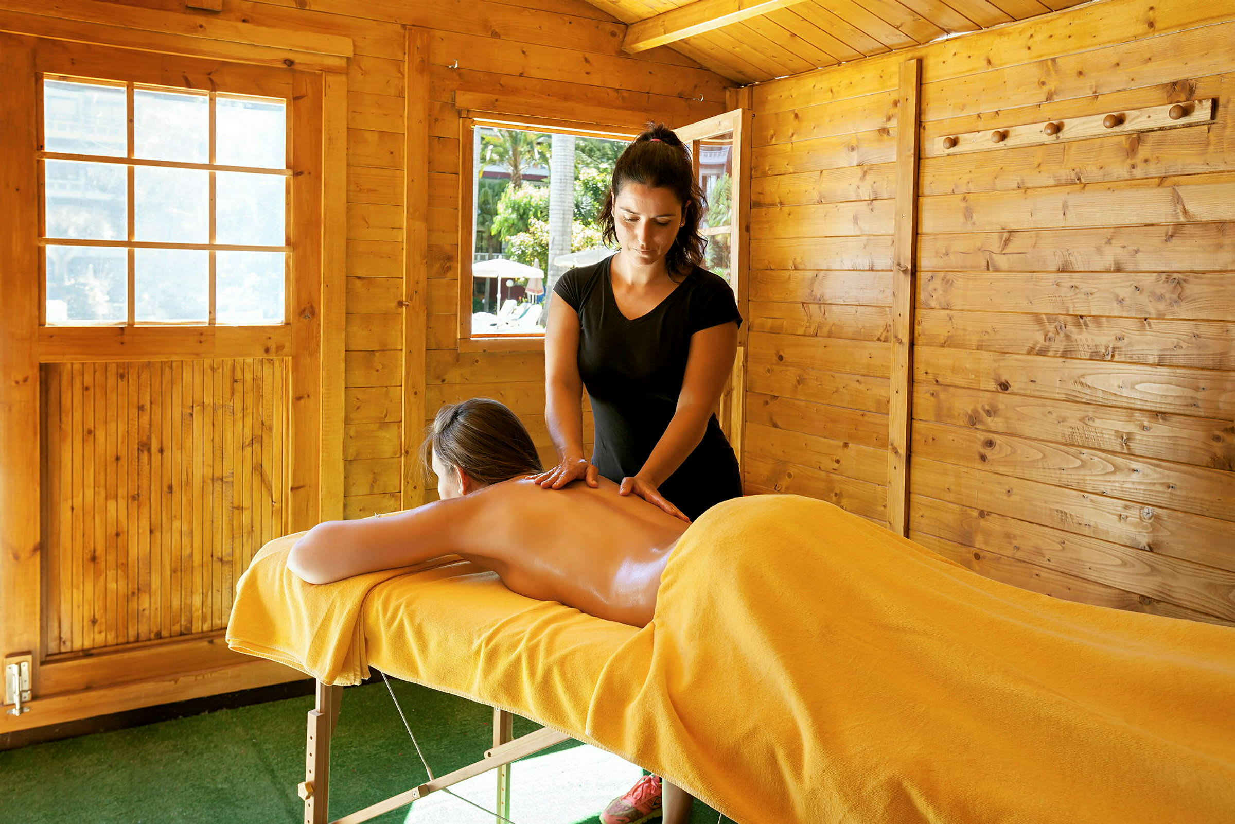 Person modtager rygmassage i træbygning. (AI-genereret tekst)