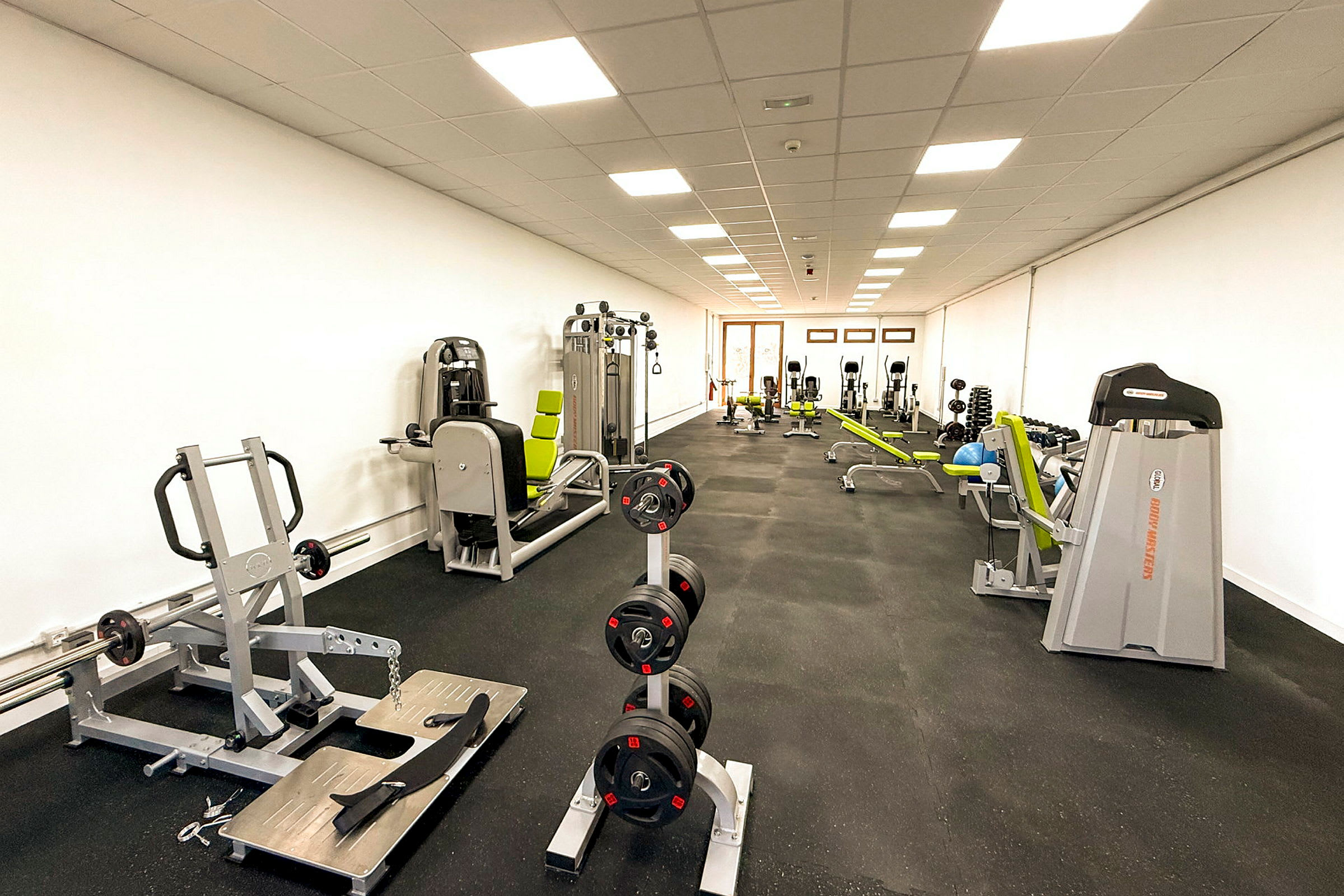 Et fitnesscenter med træningsmaskiner og styrketræningsudstyr. (AI-genereret tekst)