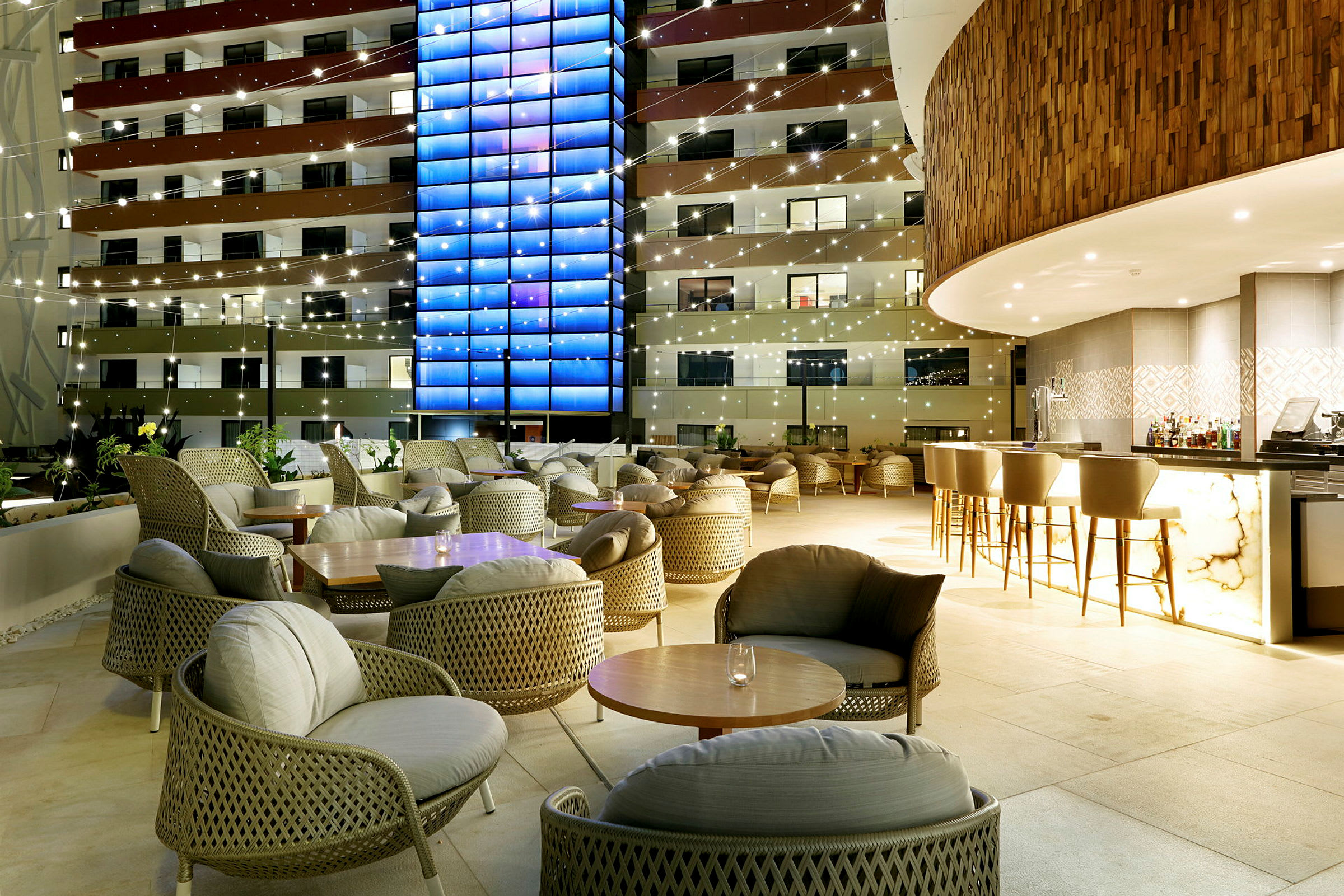 En oplyst hotelbar og siddegrupper på en terrasse om aftenen. (AI-genereret tekst)