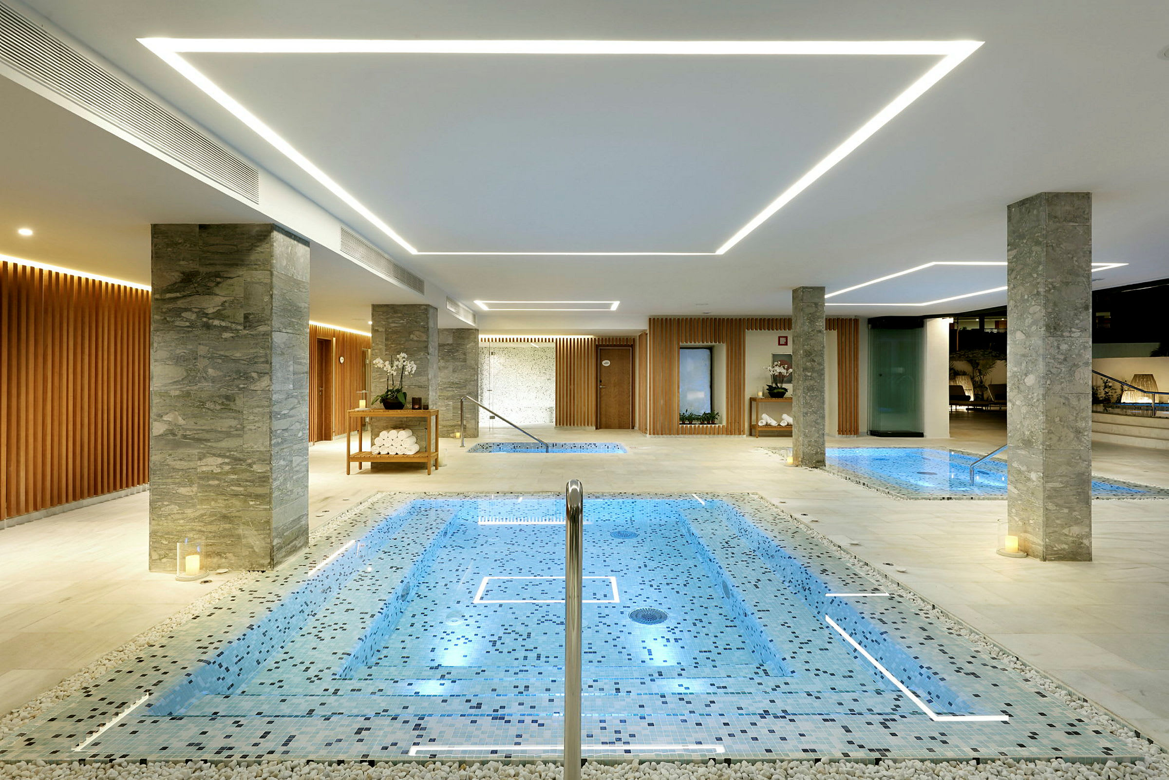 Indendørs poolområde med flere små pools og moderne belysning. (AI-genereret tekst)