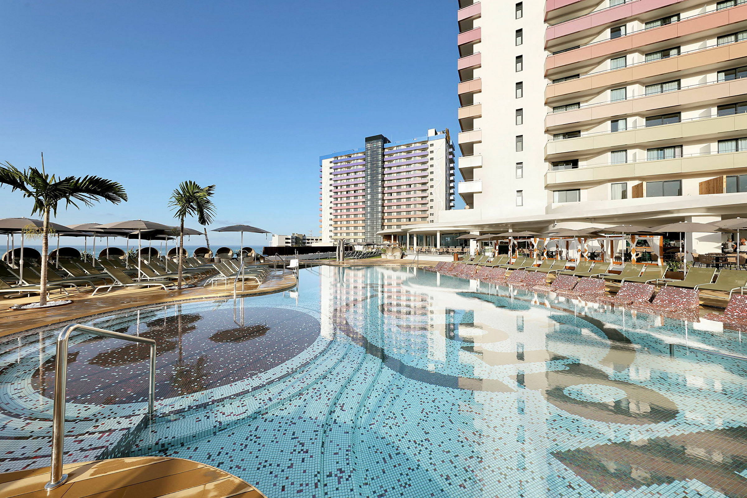 En udendørs pool ved et hotel med liggestole og parasoller. (AI-genereret tekst)