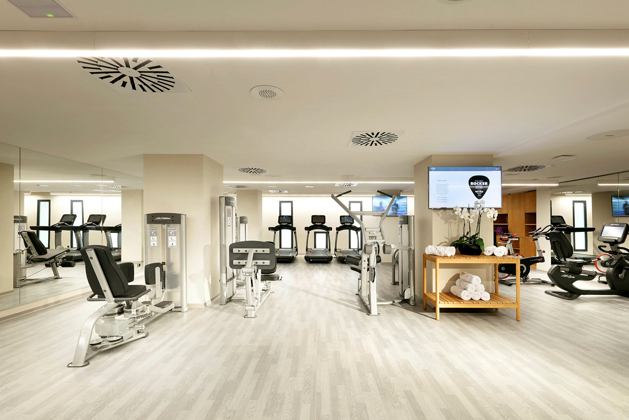Fitnesscenter med træningsudstyr, løbebånd og cykelmaskiner. (AI-genereret tekst)