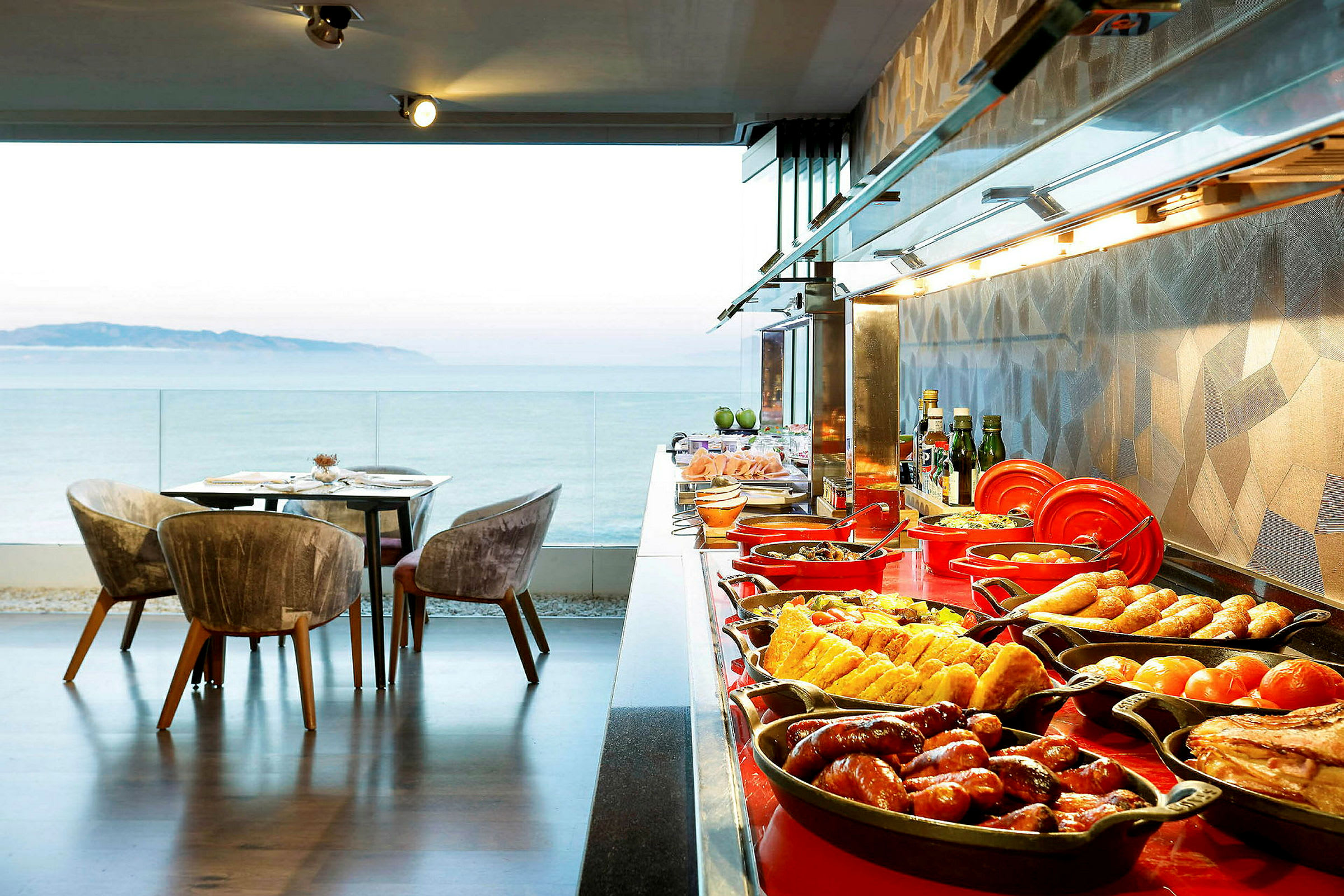 Billede af en buffet med mad og en siddegruppe nær en panoramaudsigt over havet. (AI-genereret tekst)