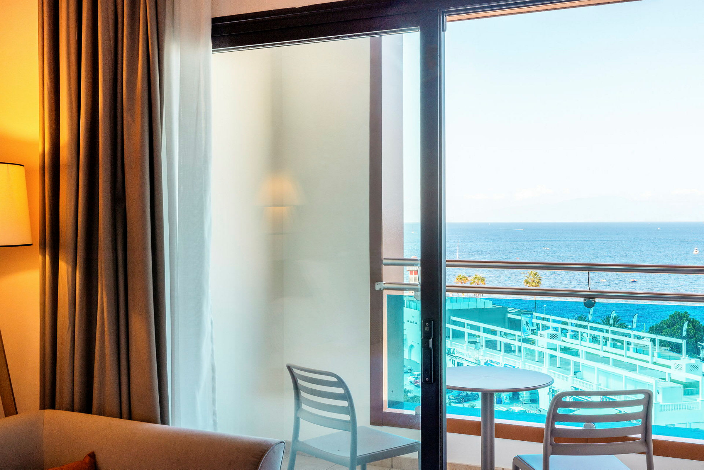 Billede af hotelværelse med udsigt til en balkon, med havet i baggrunden. (AI-genereret tekst)