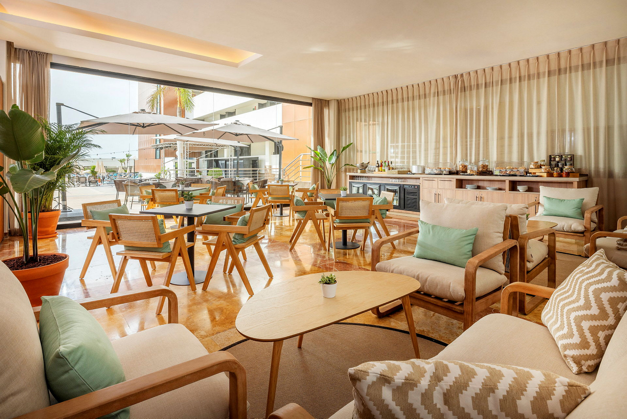 En elegant lounge med træmøbler og stofftæpper. Udsigt til en udendørs pool med parasoller. (AI-genereret tekst)