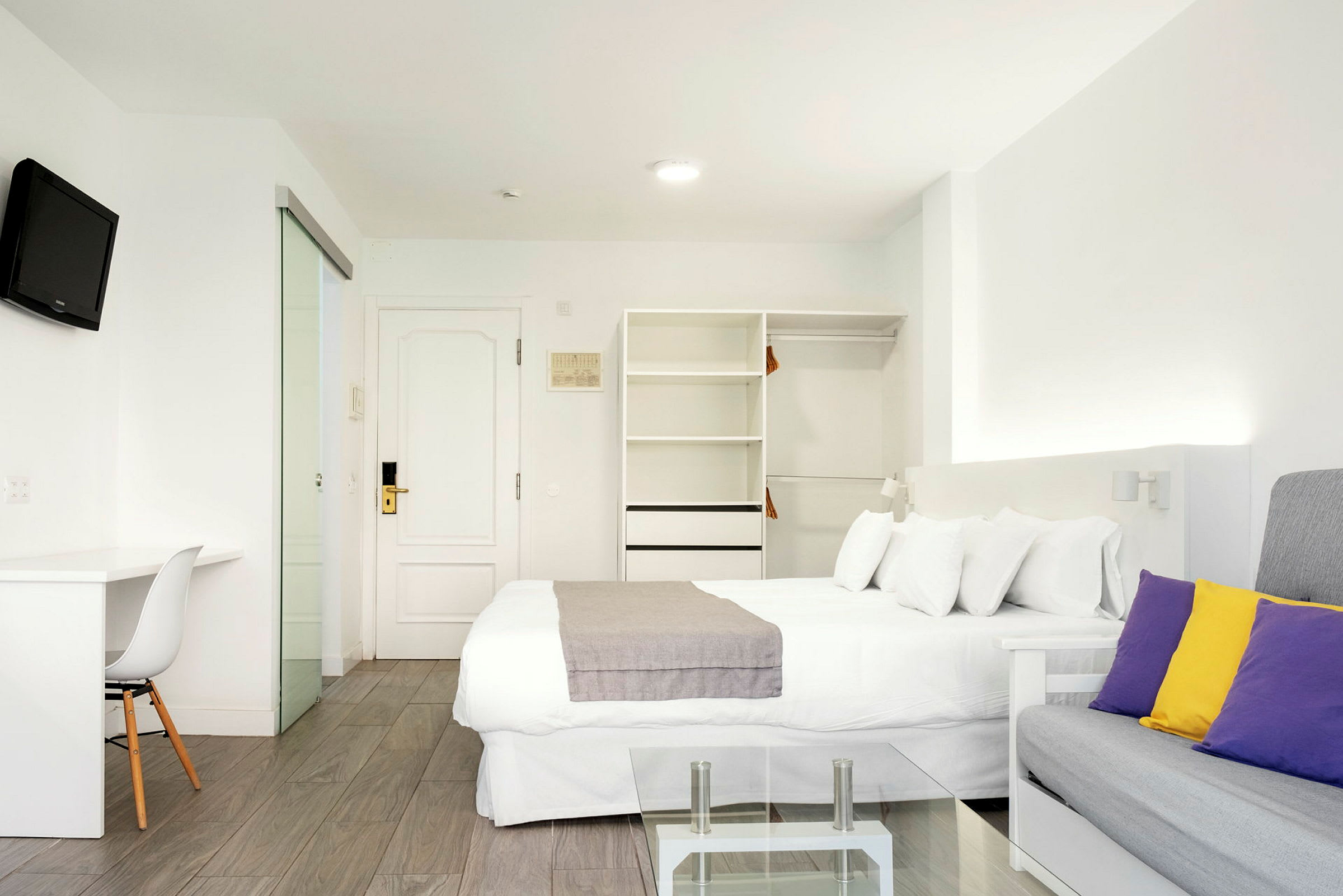 Moderne hotelværelse med hvidt interiør og farvede puder. (AI-genereret tekst)