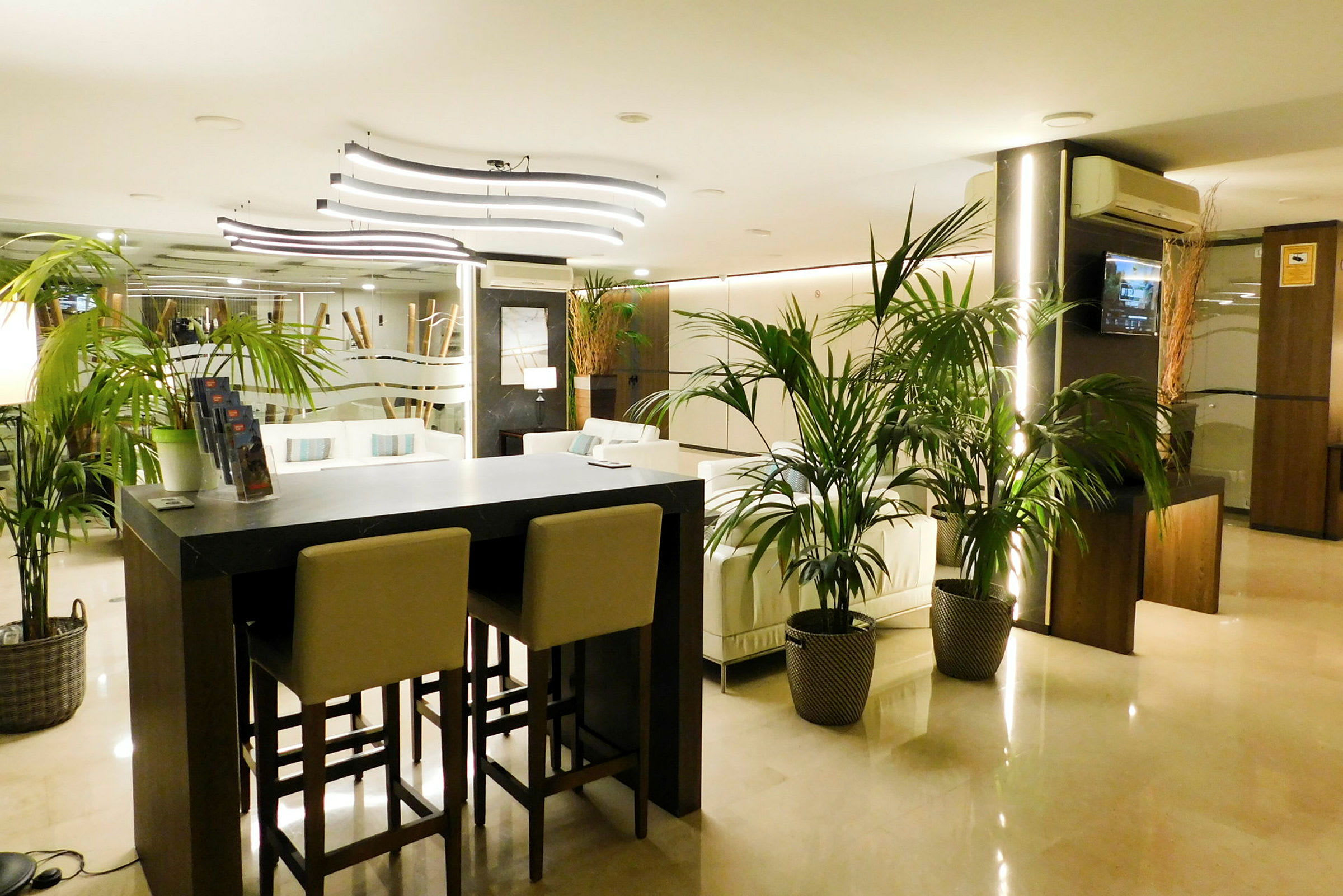 Hotellets lobby med moderne indretning, sofaer og planter. (AI-genereret tekst)