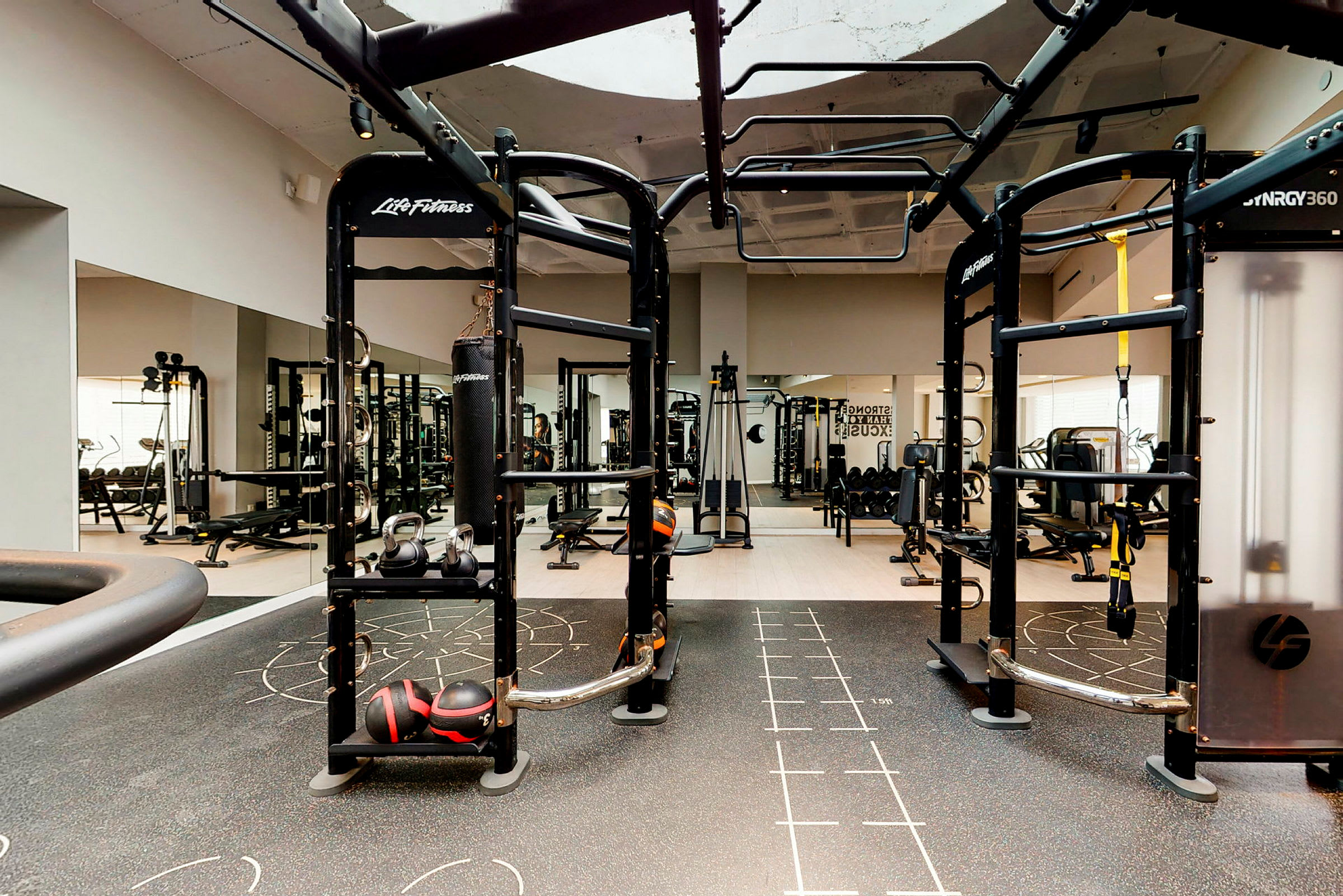 Et fitnesscenter med forskellige træningsredskaber som kettlebells, boksebold og styrketræningsmaskiner. (AI-genereret tekst)
