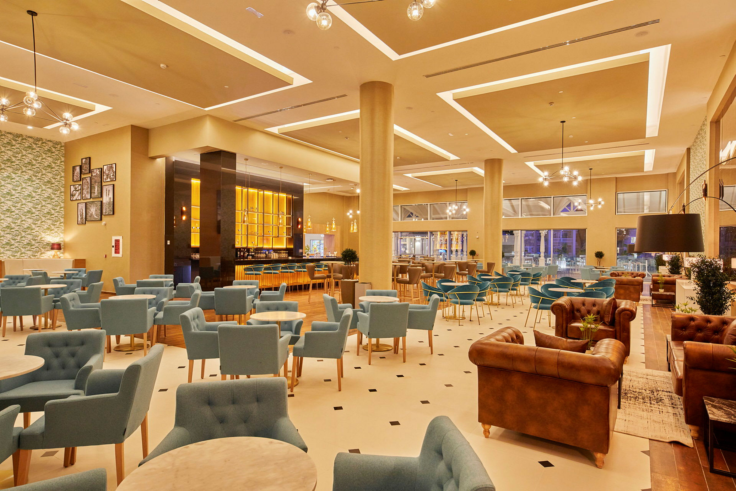 Et moderne hotelområde med siddegrupper og en oplyst bar. (AI-genereret tekst)