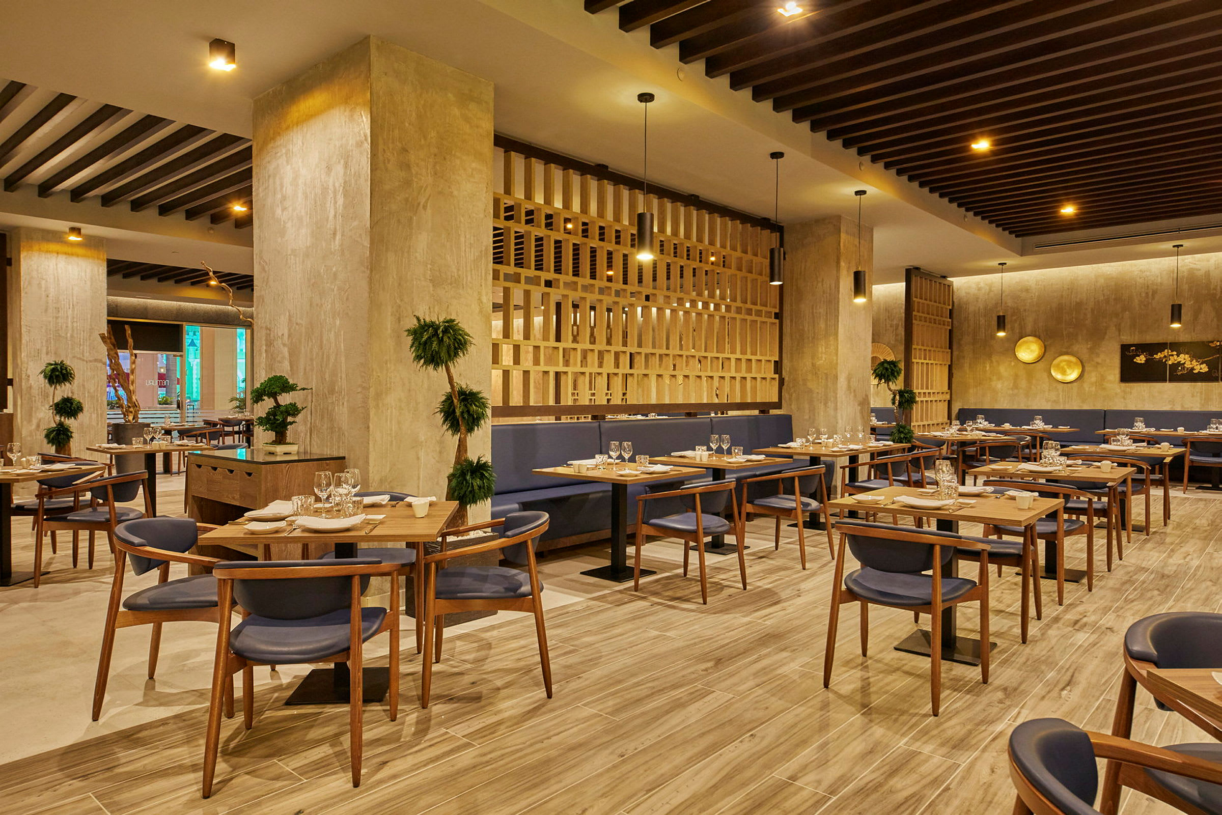 En moderne restaurant med træinteriør, borde med opdækning og blå stole. (AI-genereret tekst)