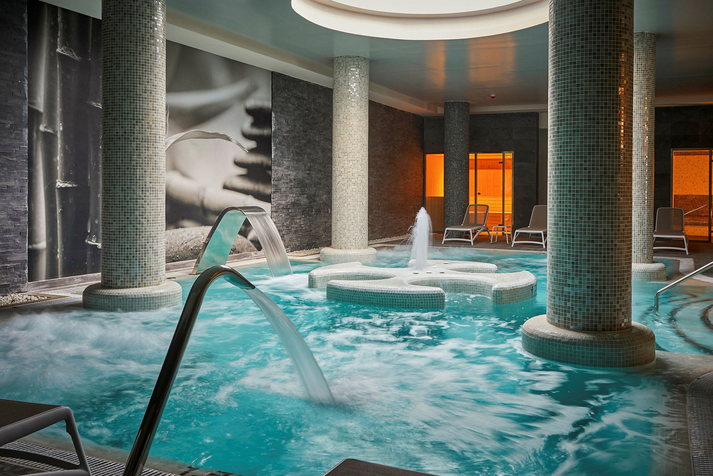 Indendørs spa med pool, vandstråler og liggestole. (AI-genereret tekst)