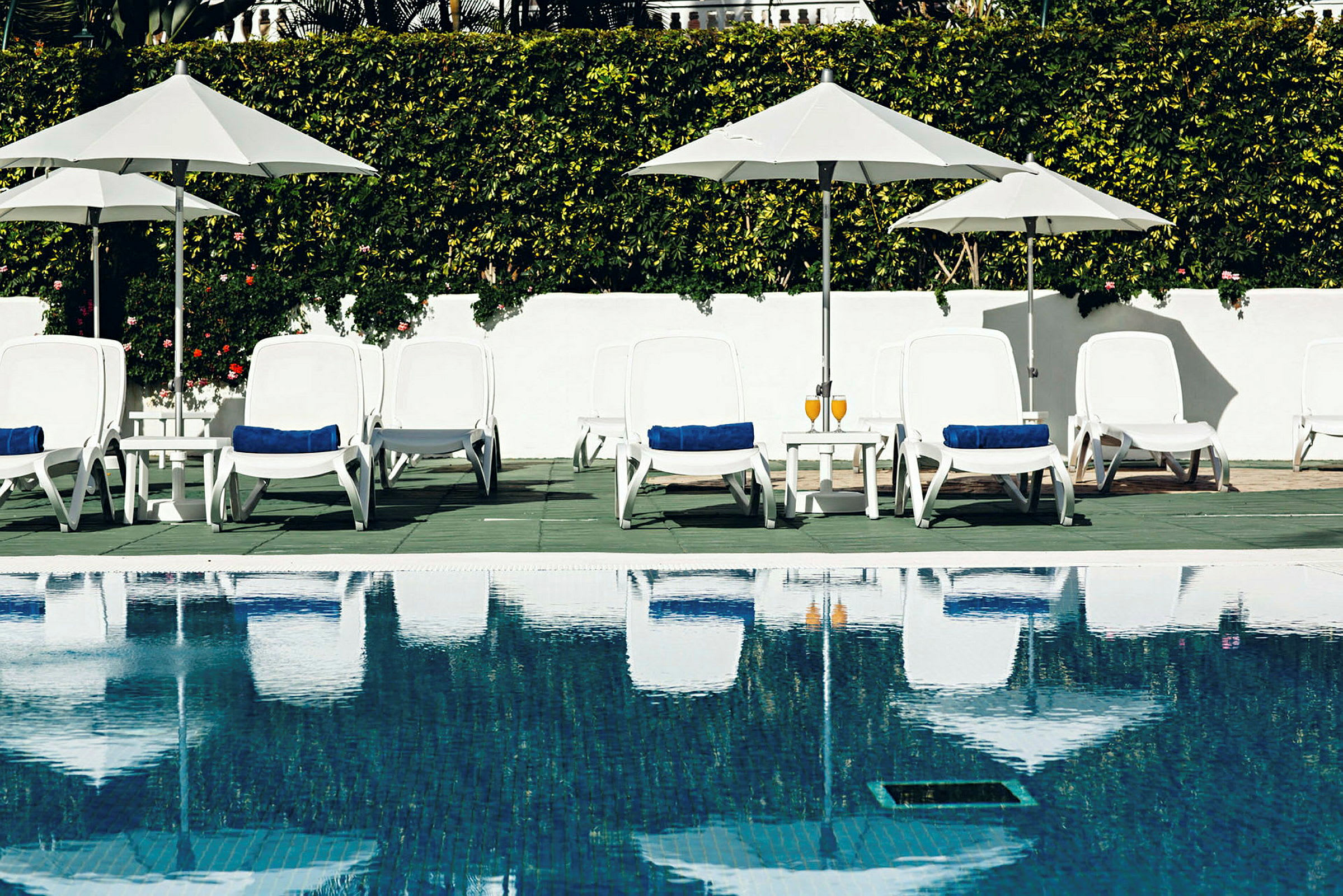 Liggestole og parasoller ved en swimmingpool. (AI-genereret tekst)