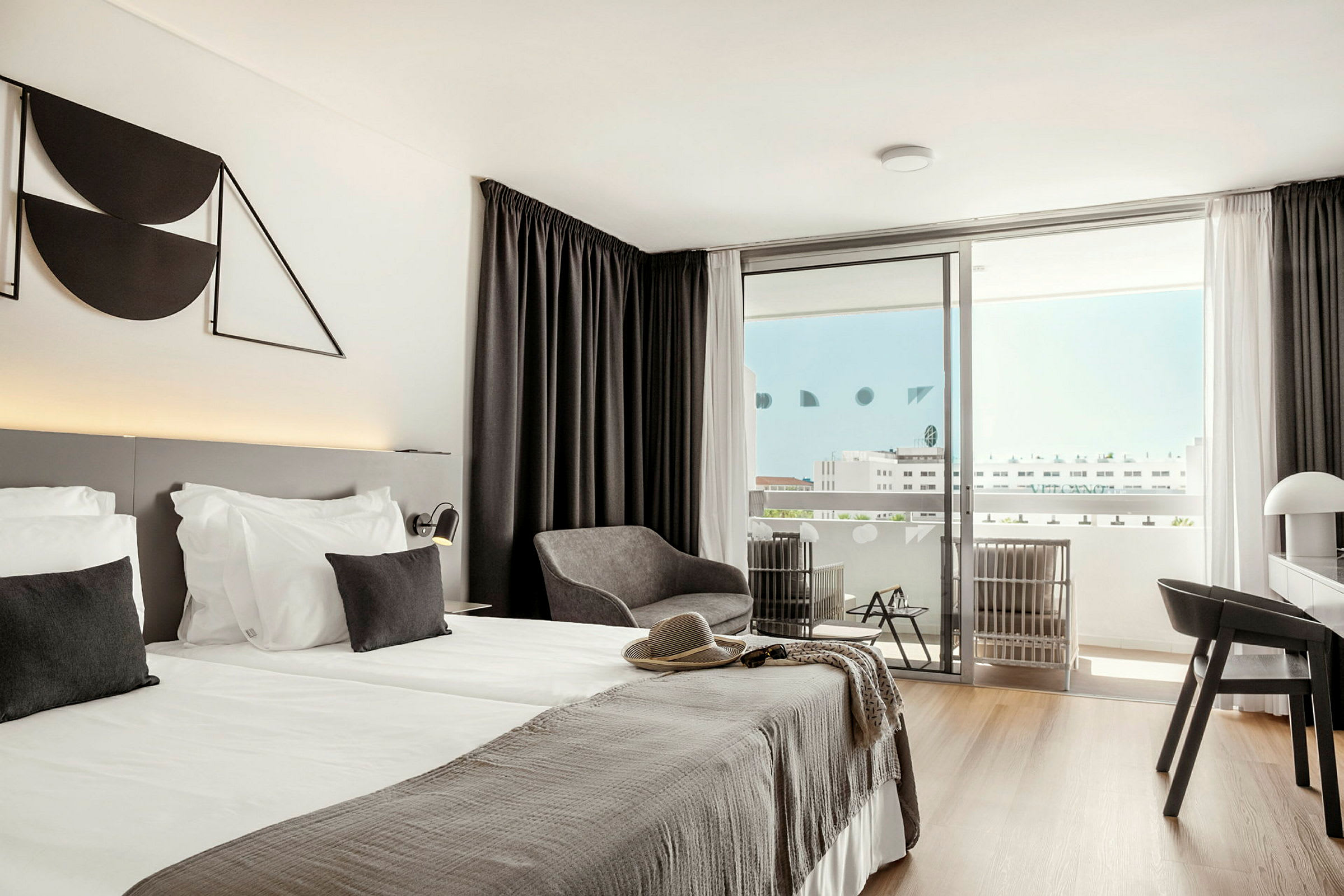 Et moderne hotelværelse med dobbeltseng, siddeområde og altan. (AI-genereret tekst)