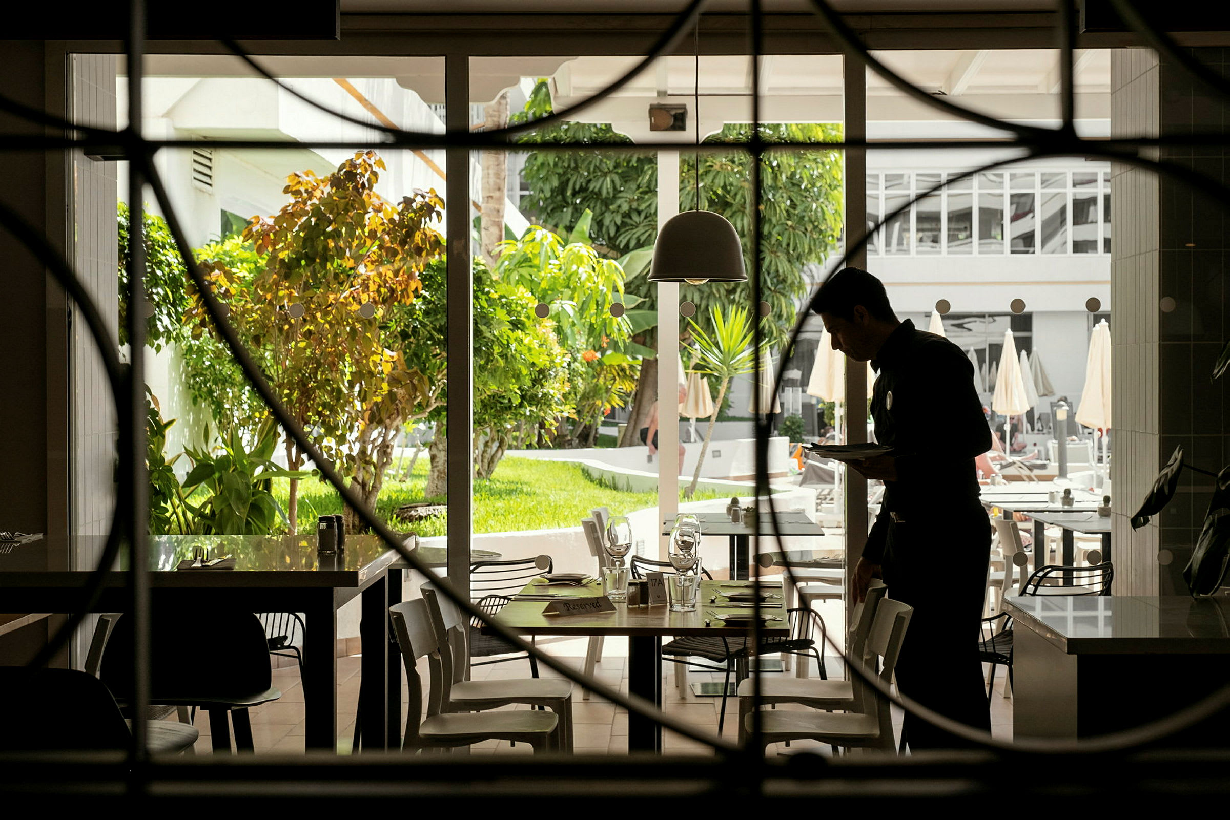 Et restaurantområde med et bord, der vender ud mod en udendørs have. (AI-genereret tekst)