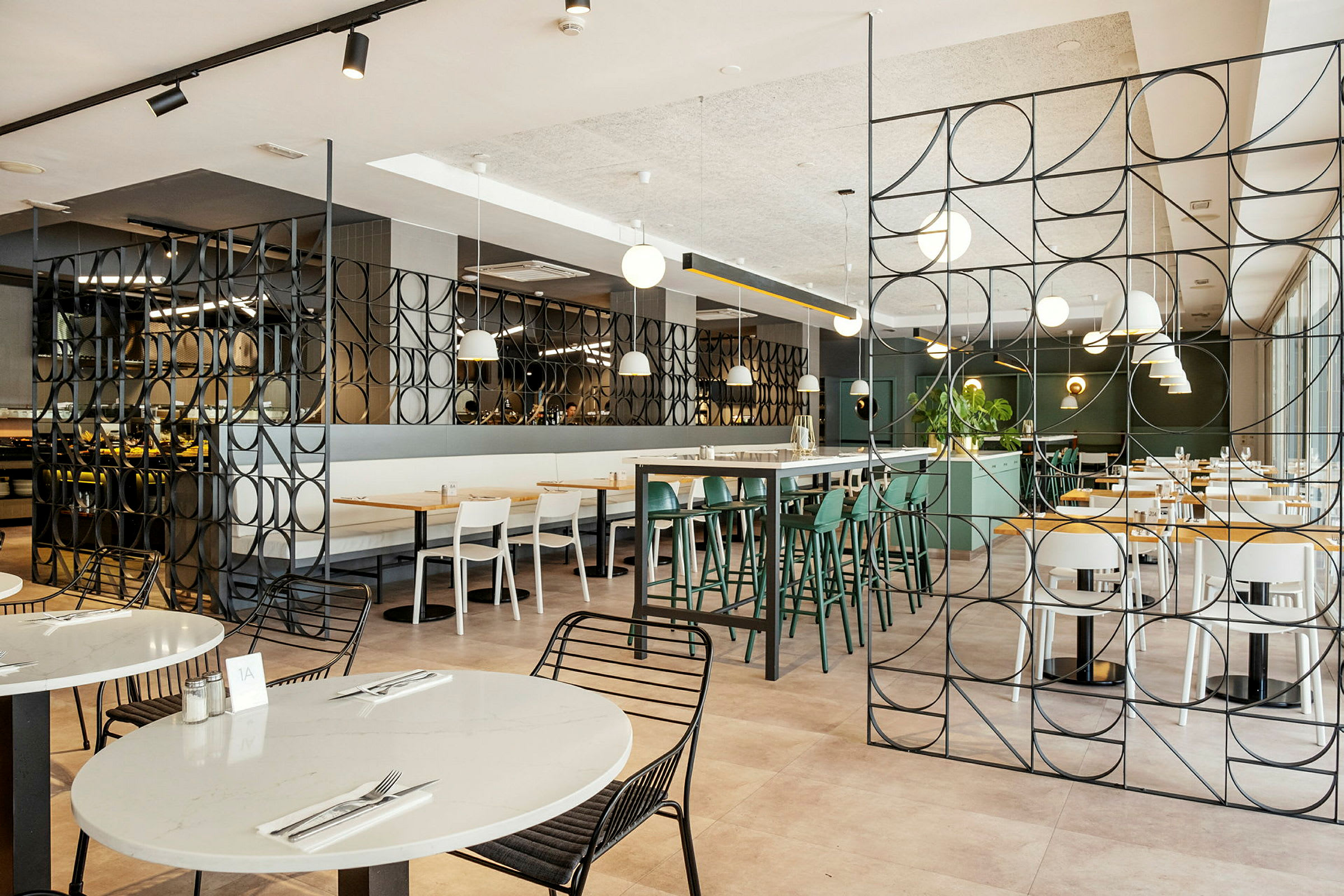 Interiør af en moderne restaurant med borde og stole samt dekorative metalpaneler. (AI-genereret tekst)