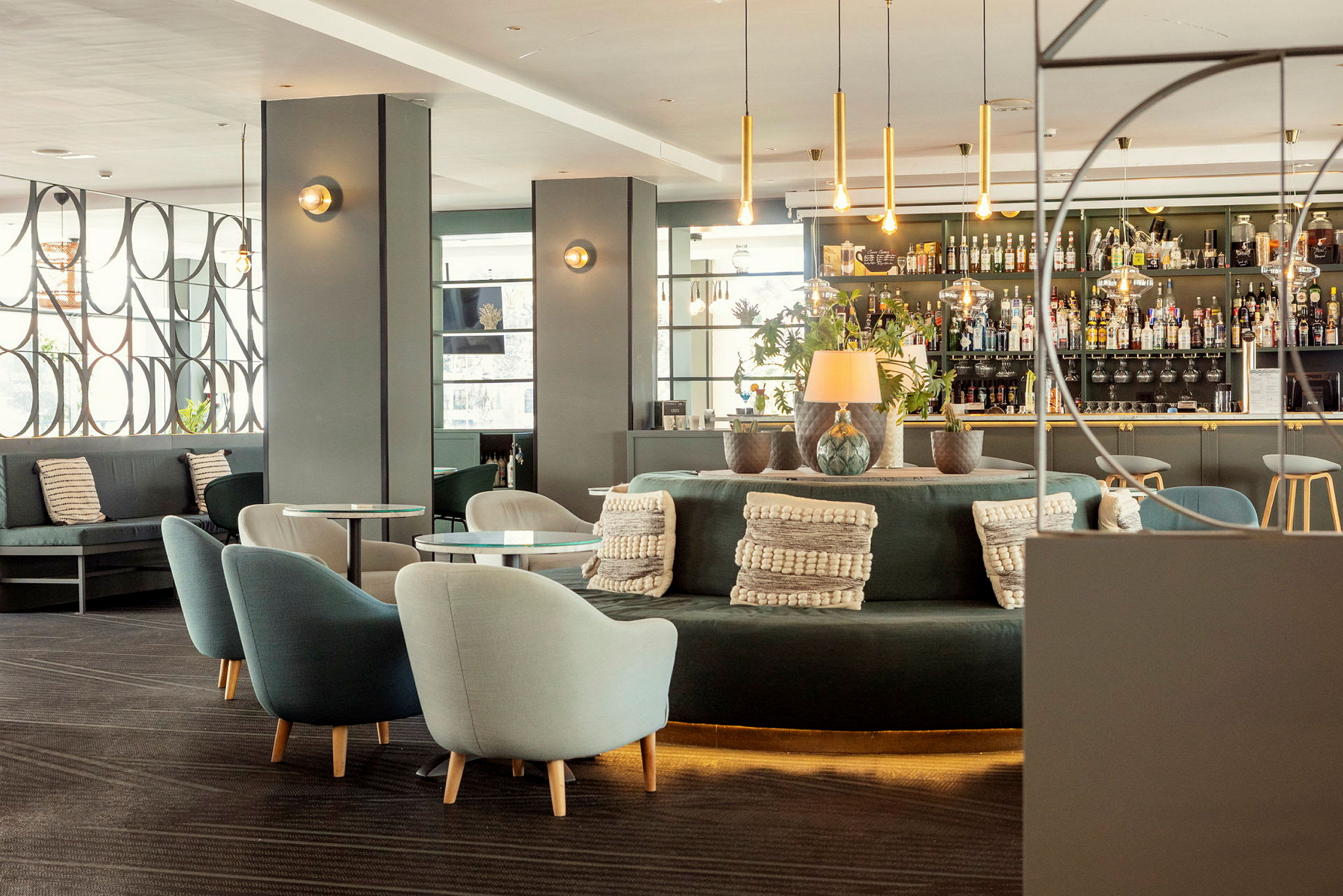 Moderne indrettet hotelbar med siddegrupper, dekorationer og hylder fyldt med flasker. (AI-genereret tekst)