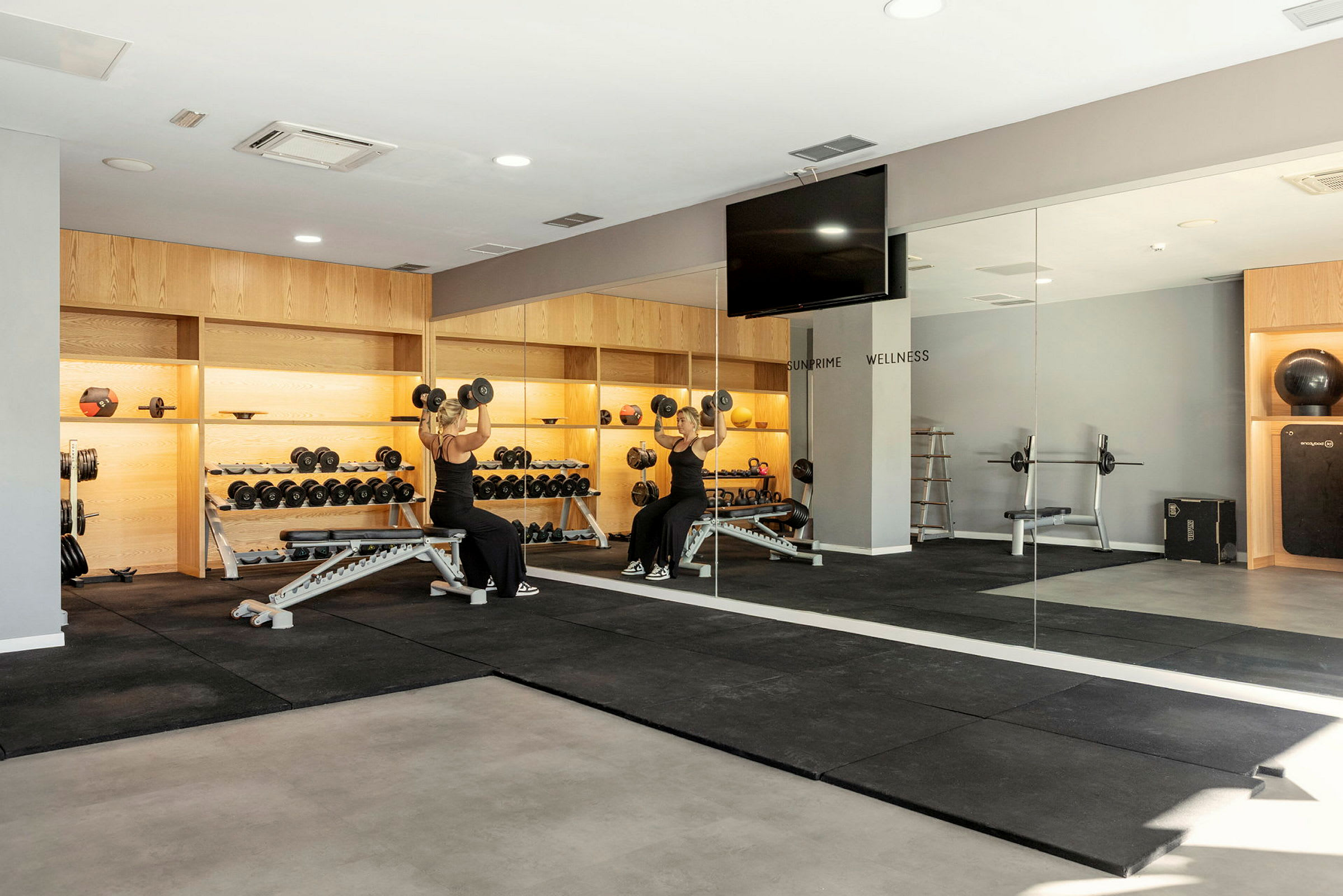 Et fitnesscenter med træningsudstyr, herunder håndvægte, spejlvæg og træningsmaskiner. (AI-genereret tekst)