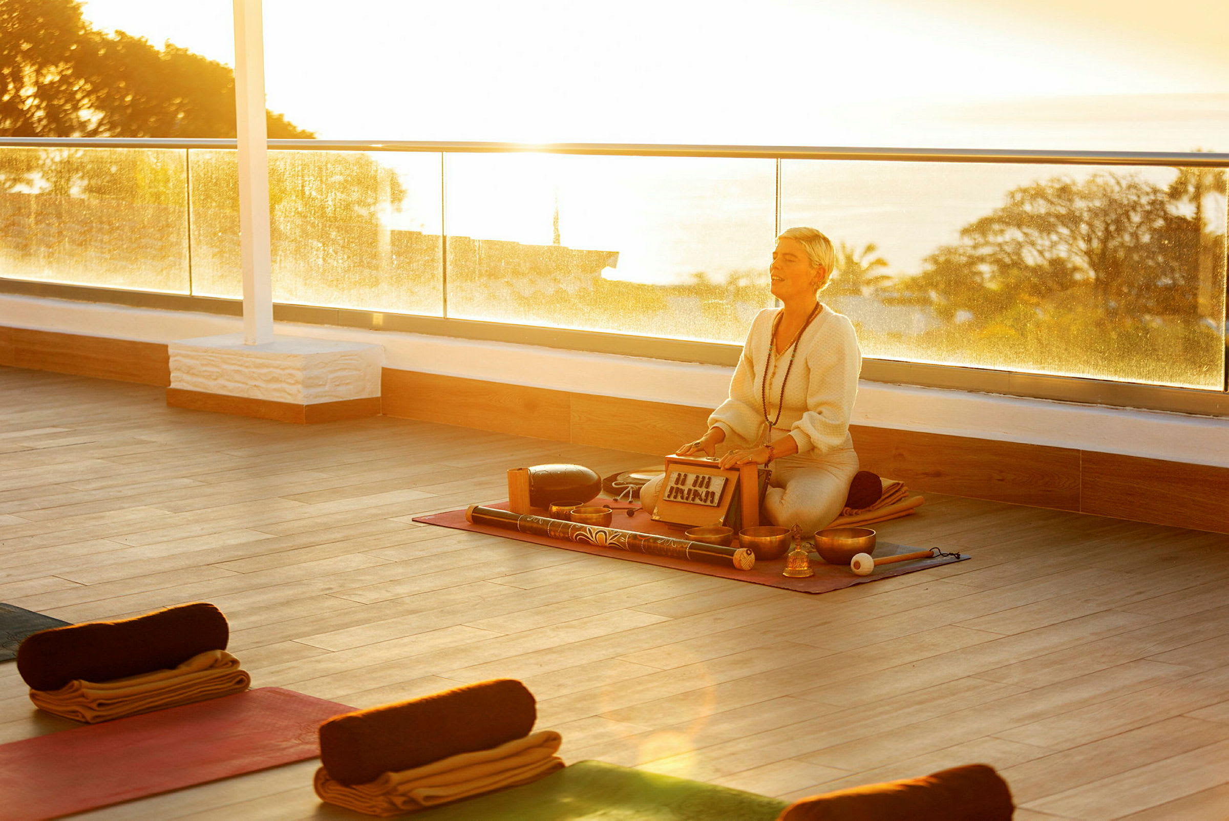 Person med instrument på yogamåtte i solnedgang. (AI-genereret tekst)