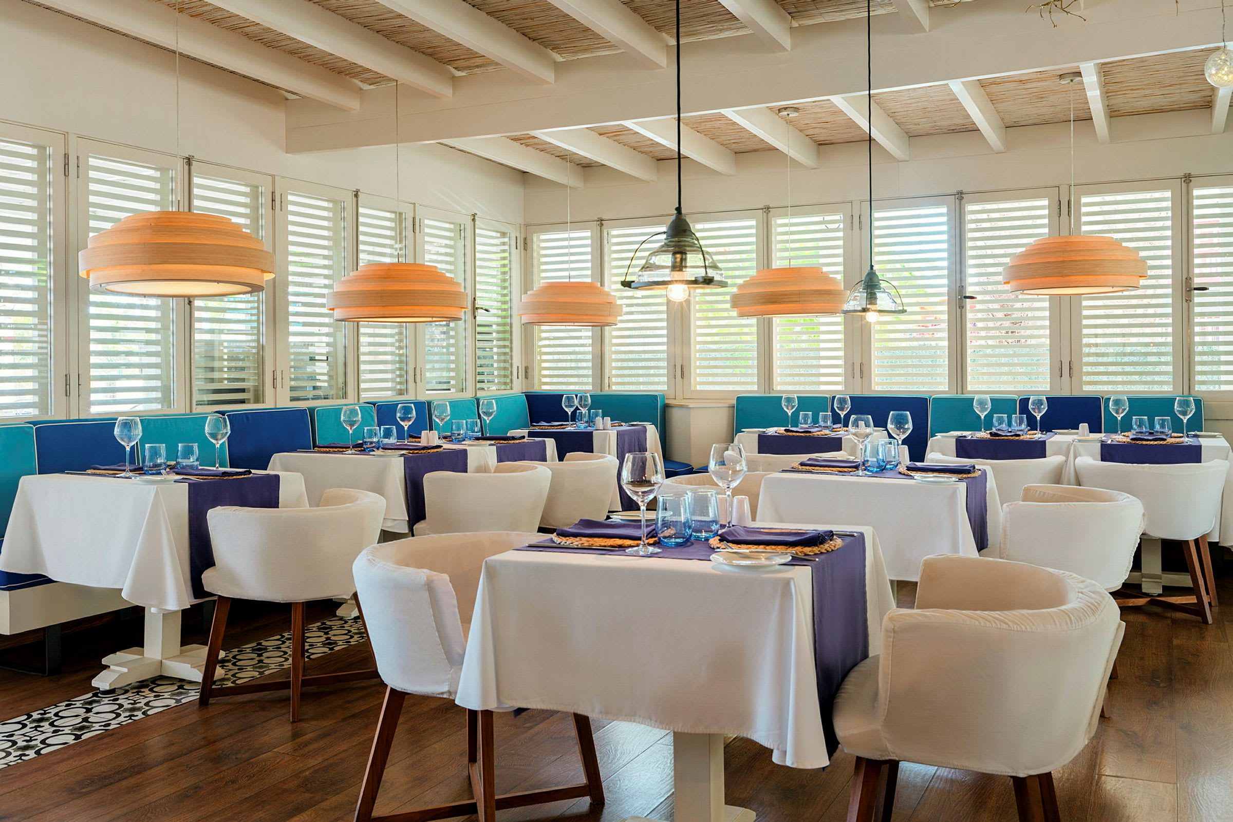 En elegant restaurant med hvide duge, blå dekoration og moderne loftslamper. (AI-genereret tekst)