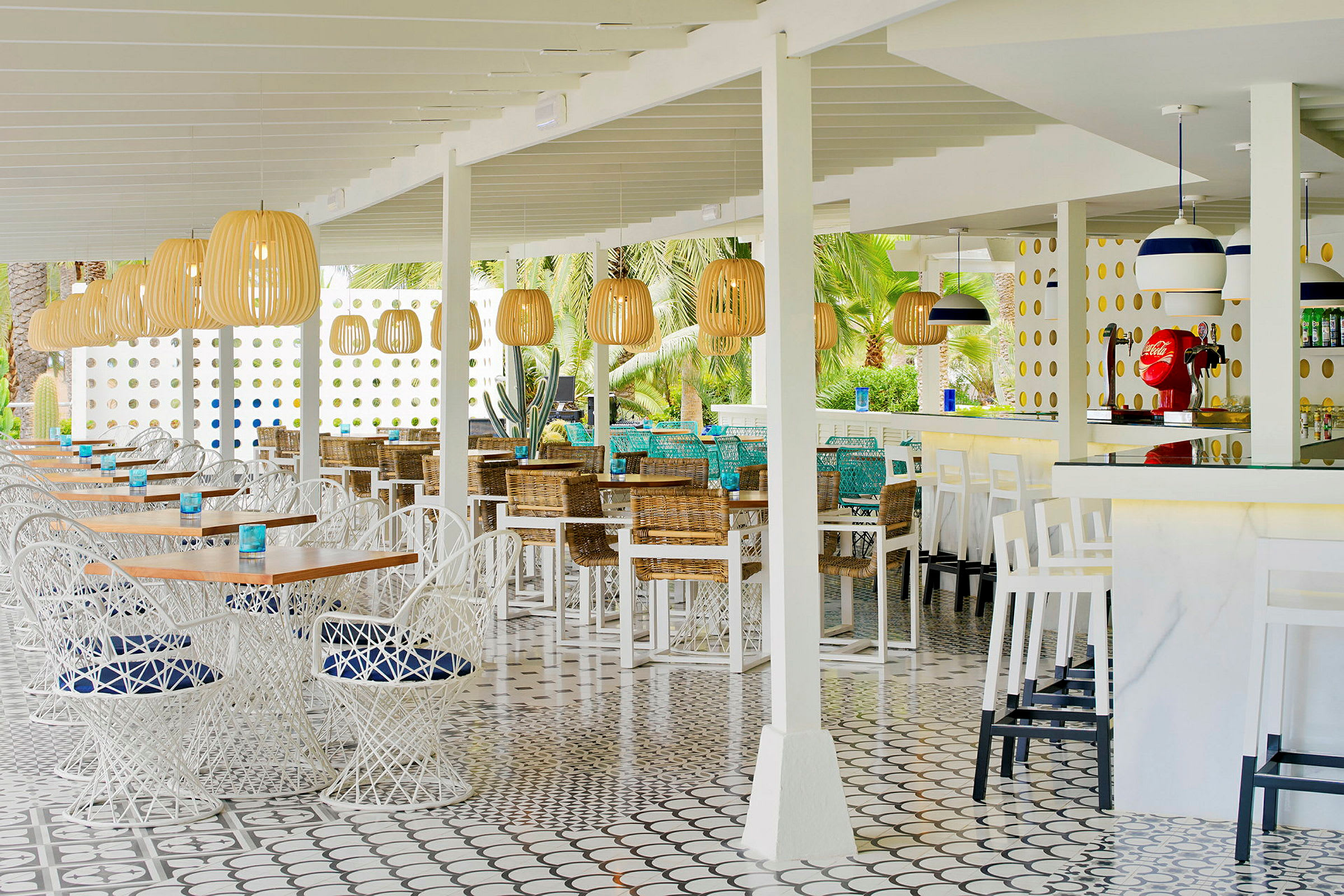 Udendørs restaurant med hvide borde og stole, kurvelamper og farverige detaljer. (AI-genereret tekst)