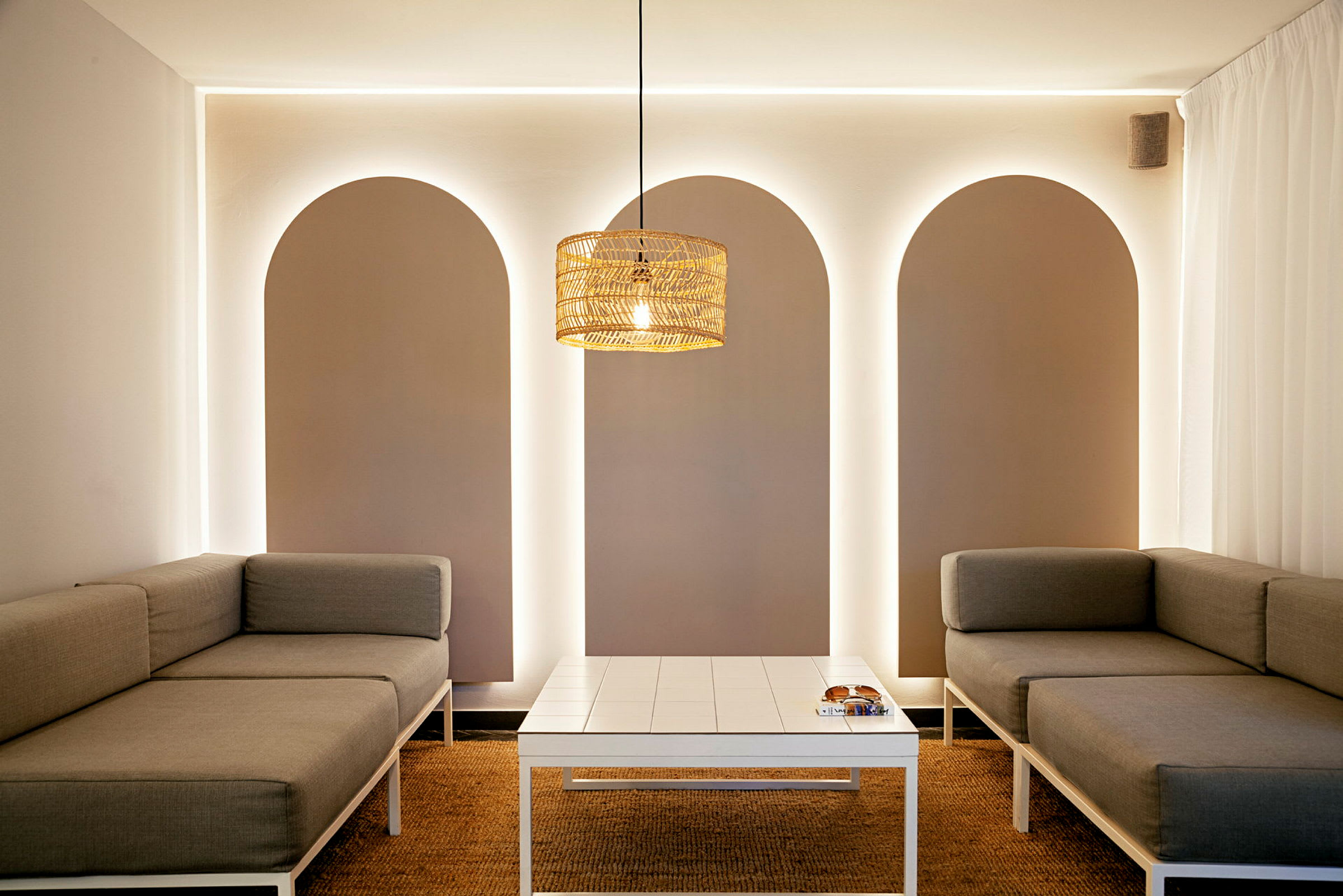 Moderne indrettet rum med grå sofaer og et hvidt bord, oplyst af en loftslampe. (AI-genereret tekst)