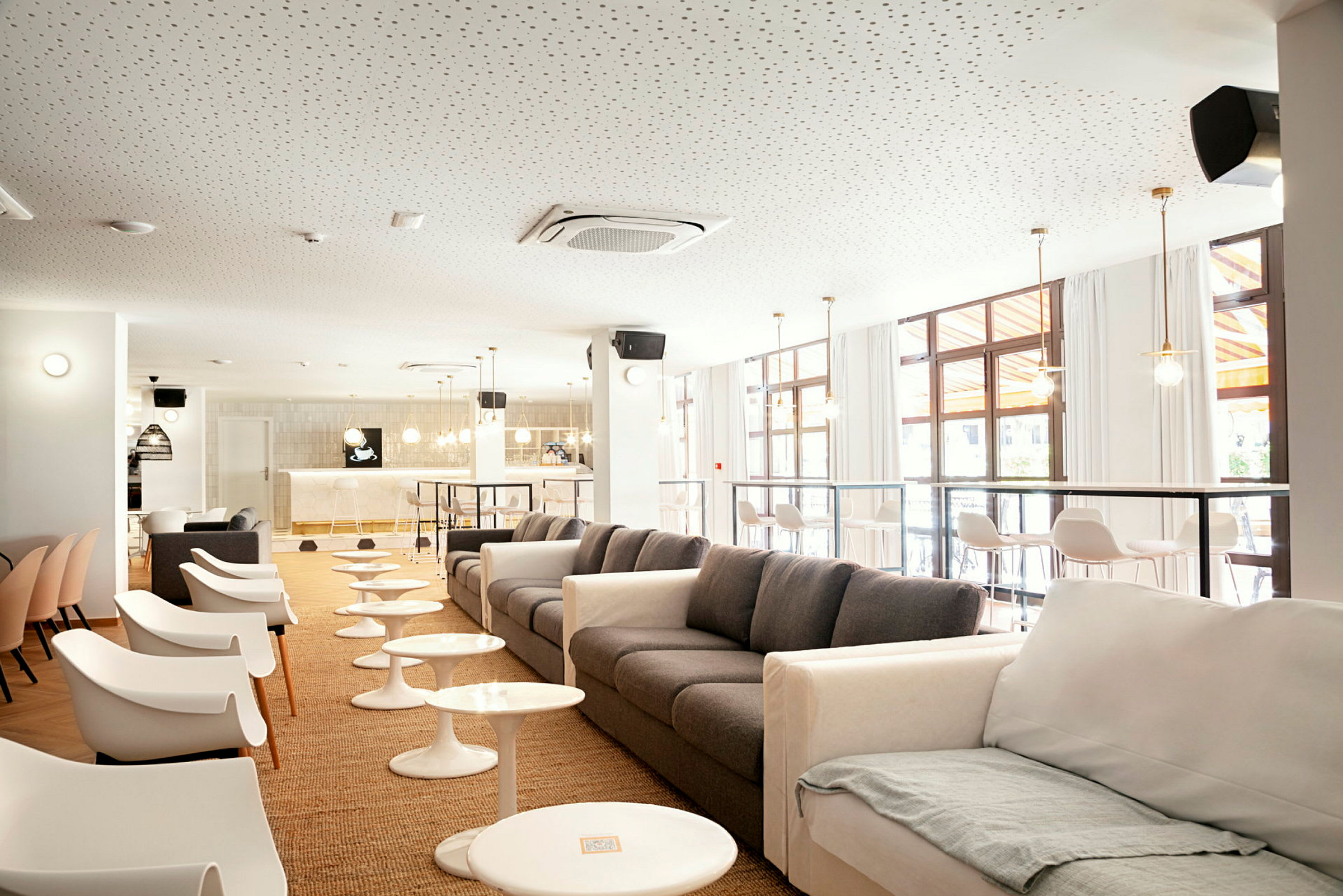 En moderne lounge med sofaer og stole, små borde og en bar i baggrunden. (AI-genereret tekst)