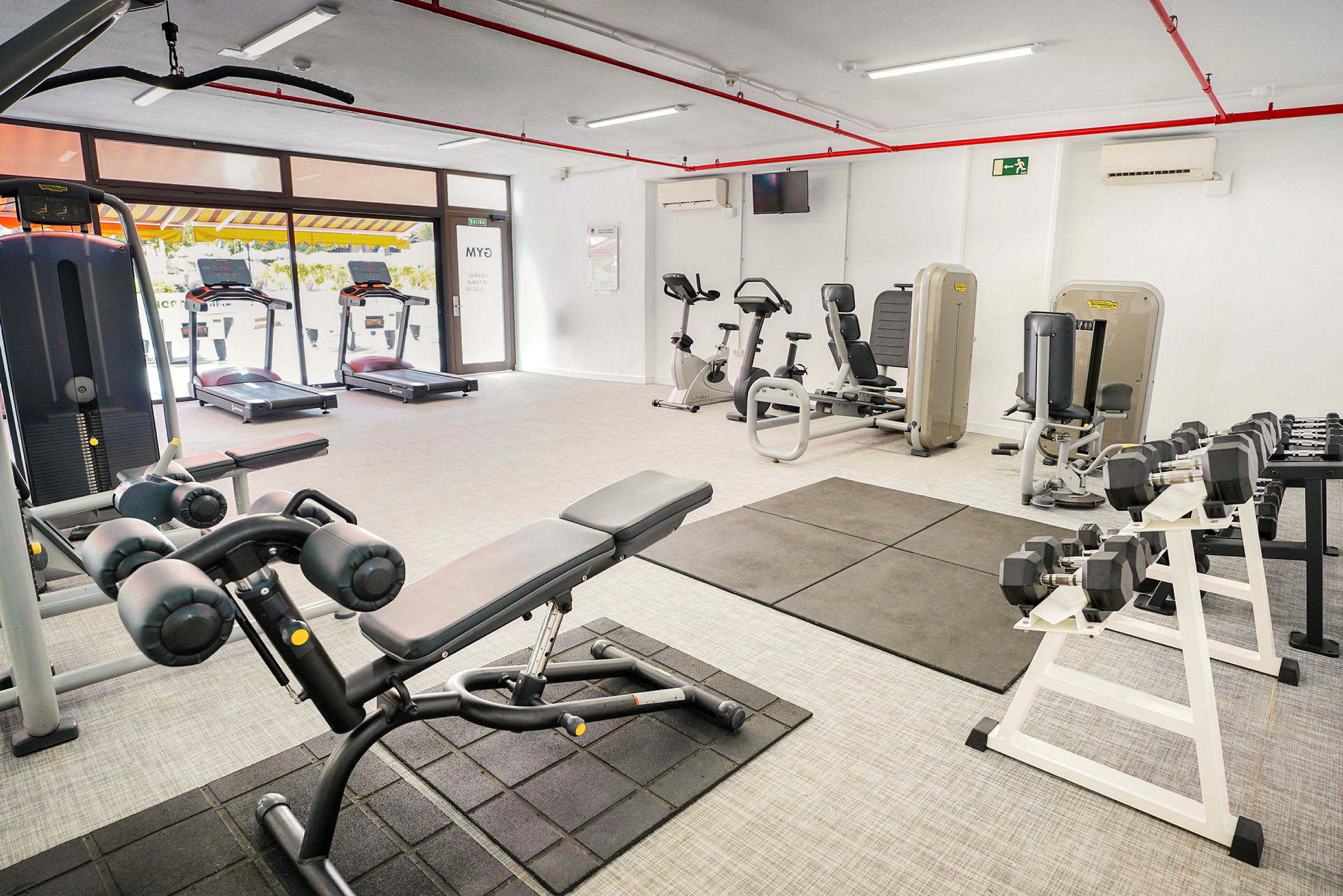 Et fitnesscenter med forskellige træningsmaskiner og vægte. (AI-genereret tekst)