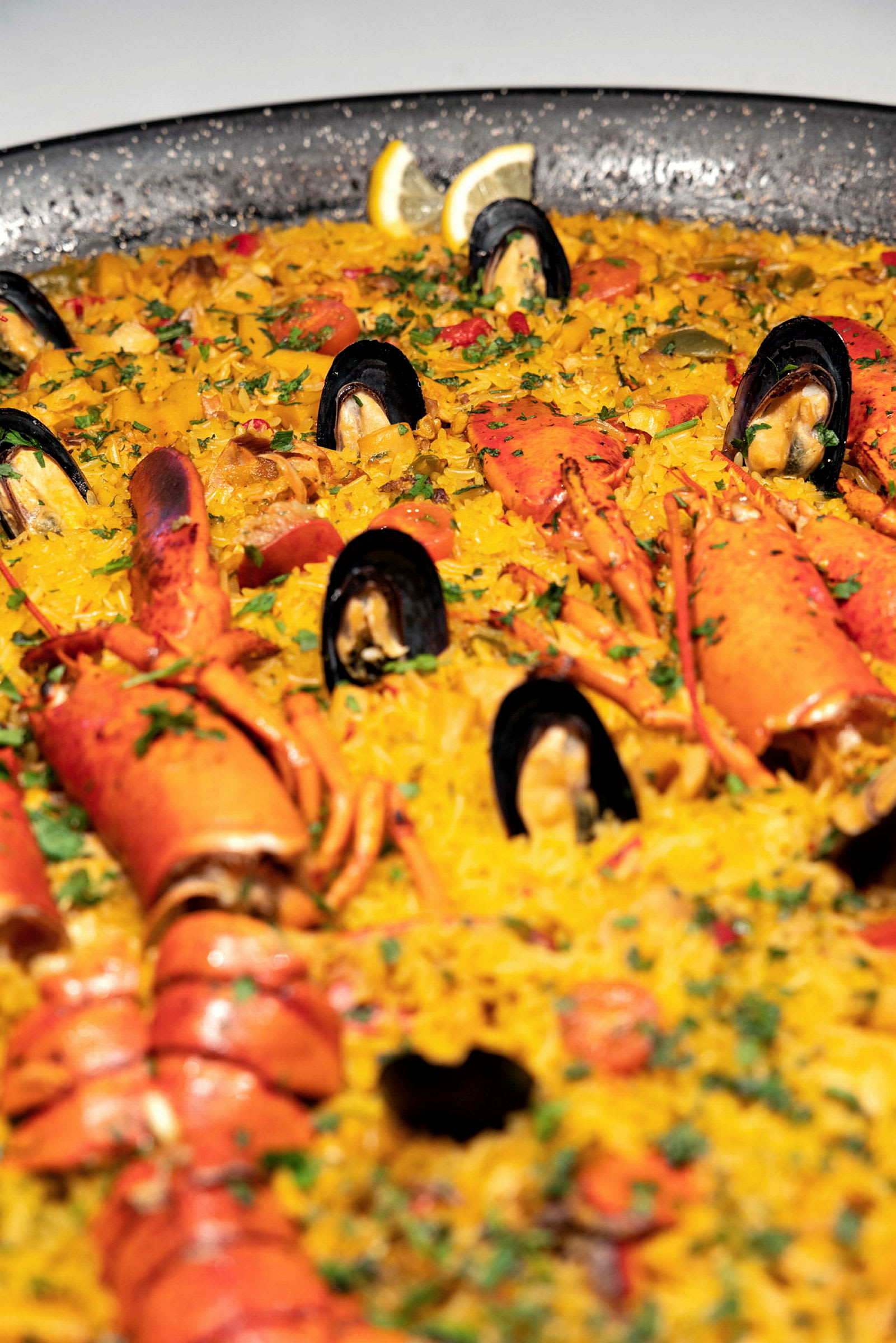 En stor paella med skaldyr, inklusive muslinger og hummer, er serveret. (AI-genereret tekst)