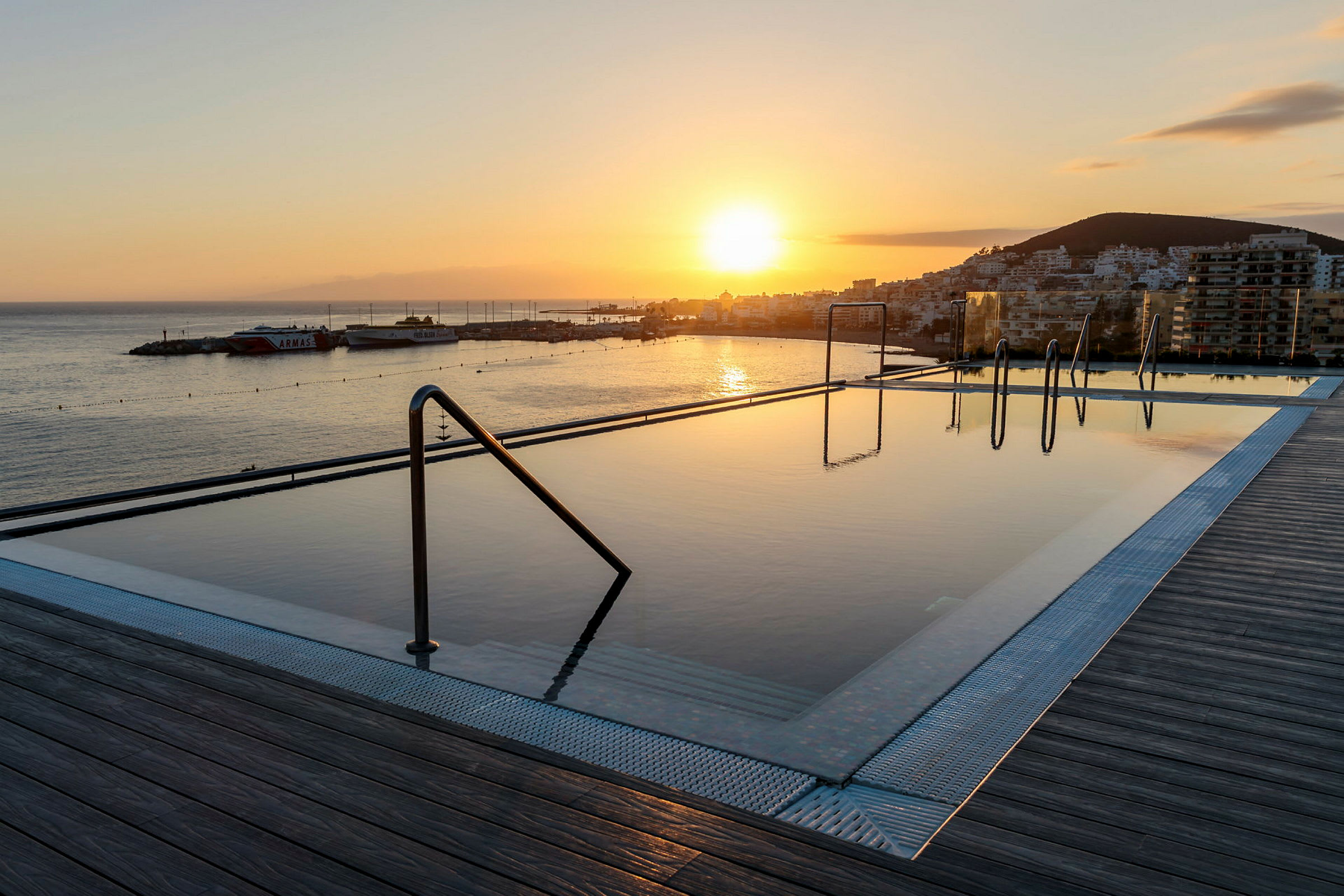 En infinity-pool med udsigt over havet ved solnedgang. (AI-genereret tekst)