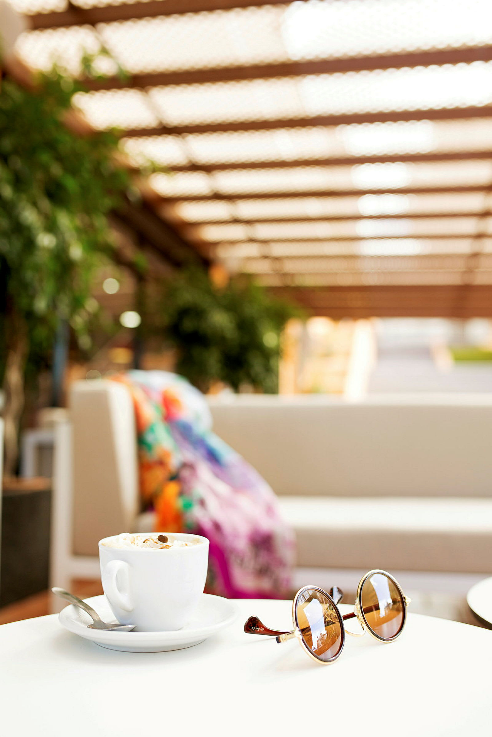 En kop kaffe og solbriller på et bord med en sofa i baggrunden. (AI-genereret tekst)