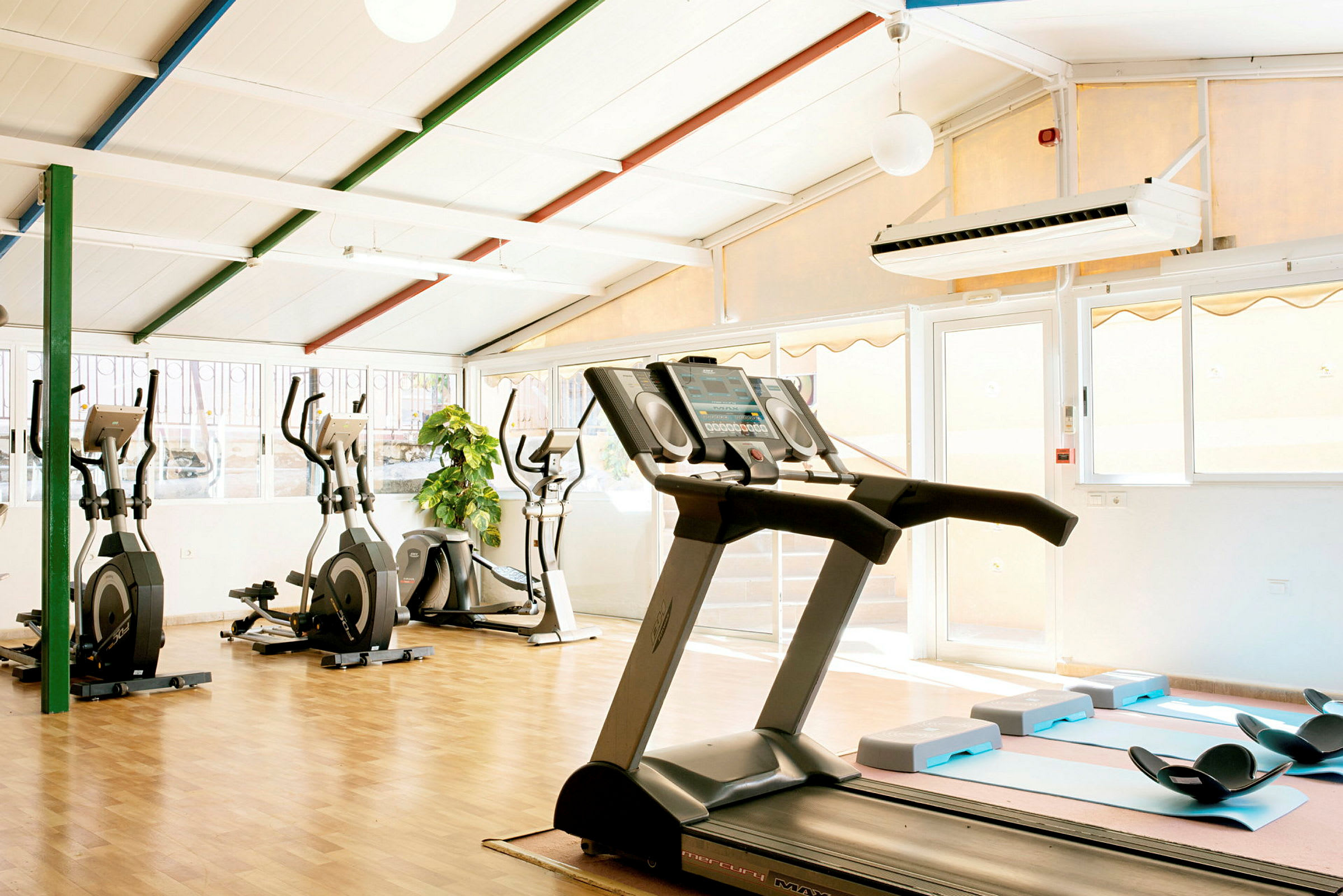 Billede af et fitnessrum med træningsmaskiner og lys interiør. (AI-genereret tekst)