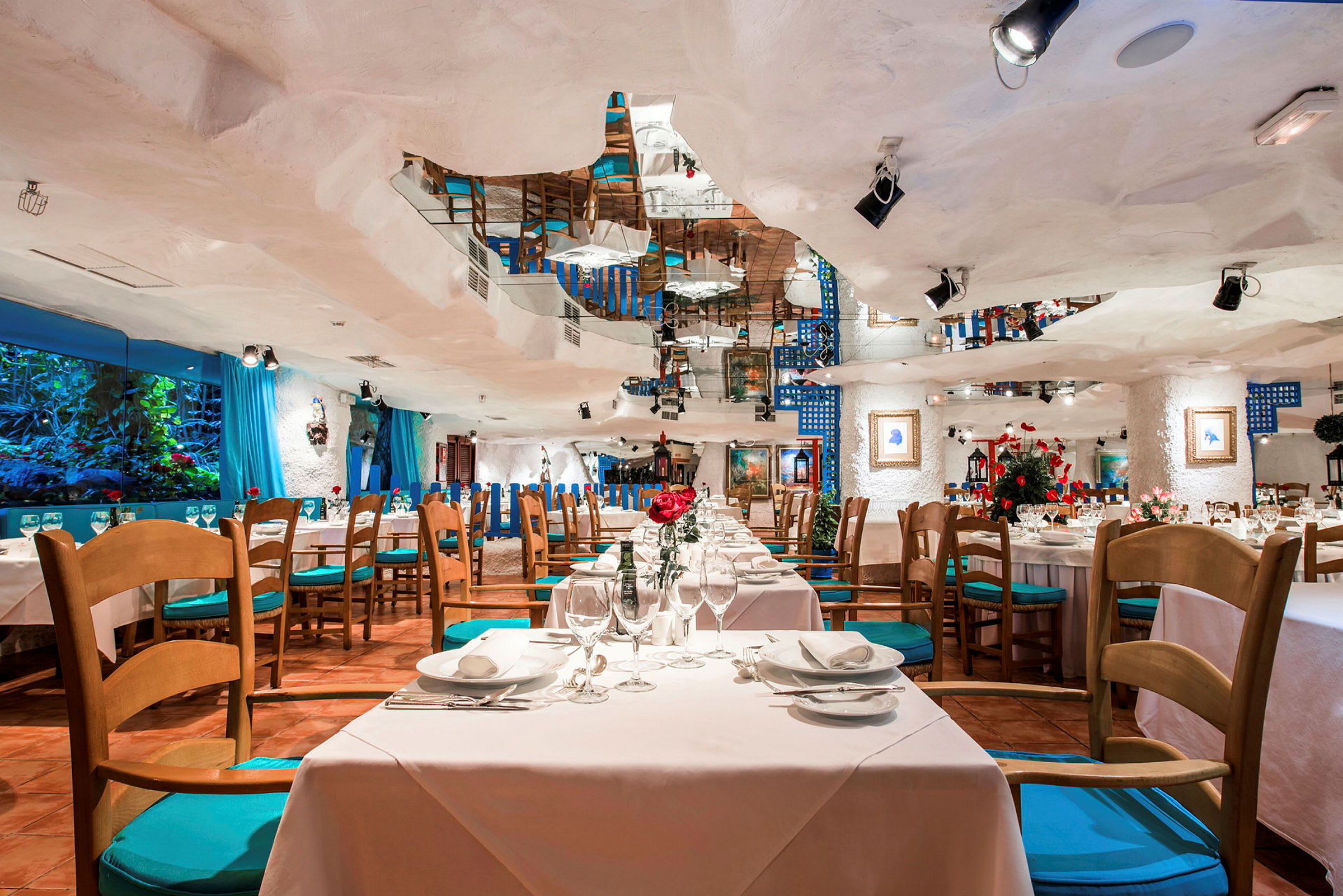 Interiøret i en restaurant med borde og stole, dekoreret med blomster og spejle. (AI-genereret tekst)
