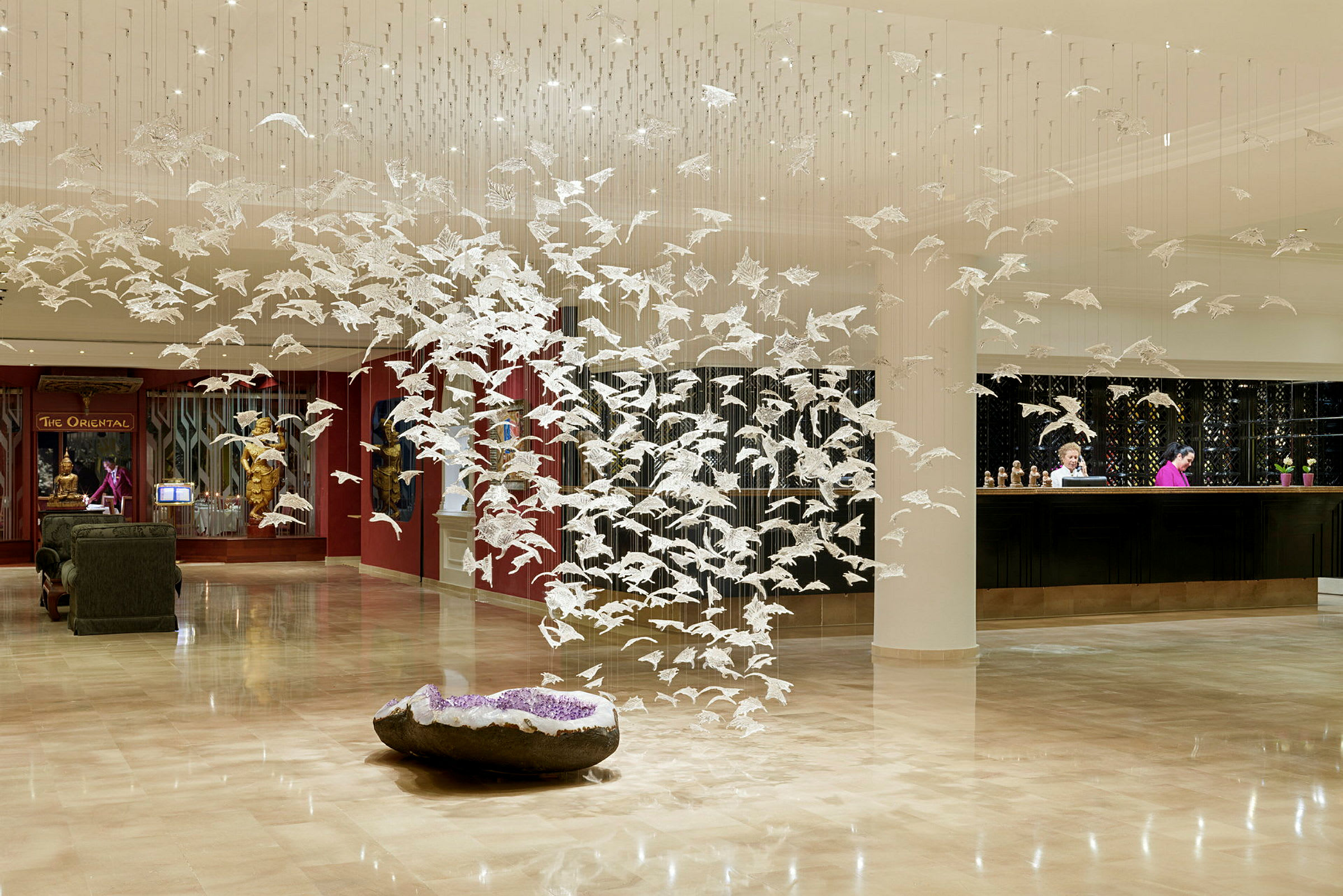 Lobby med moderne kunstinstallation af hvide fugle i hængende formation. (AI-genereret tekst)