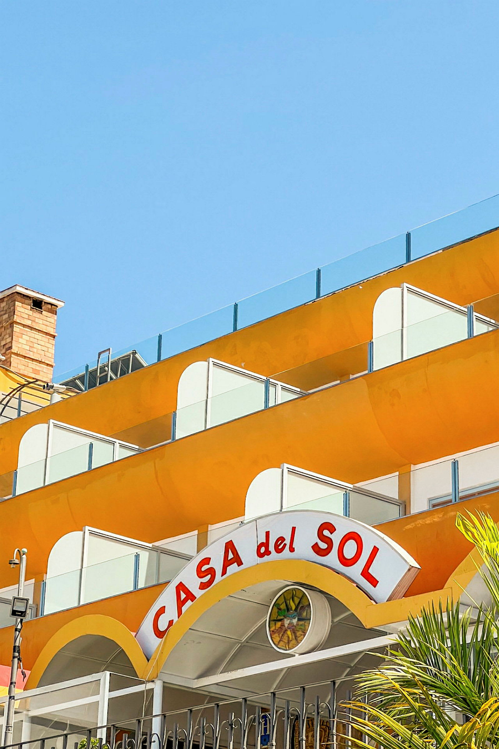 En bygning med gule altaner og et skilt med teksten "Casa del Sol". (AI-genereret tekst)