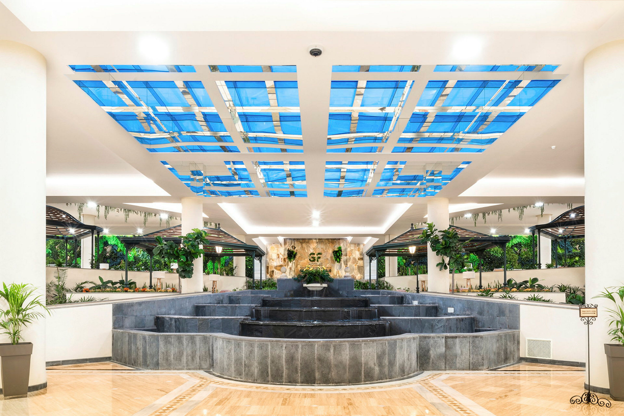 En lys og åben hotellobby med springvand og frodig indretning. (AI-genereret tekst)