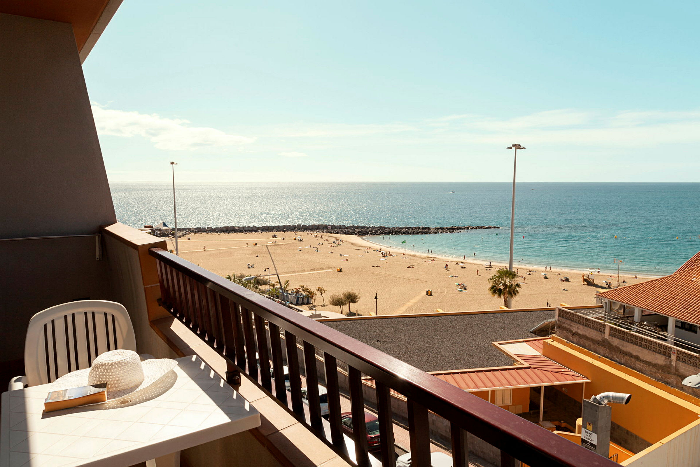En balkon med udsigt over en sandstrand og havet. (AI-genereret tekst)