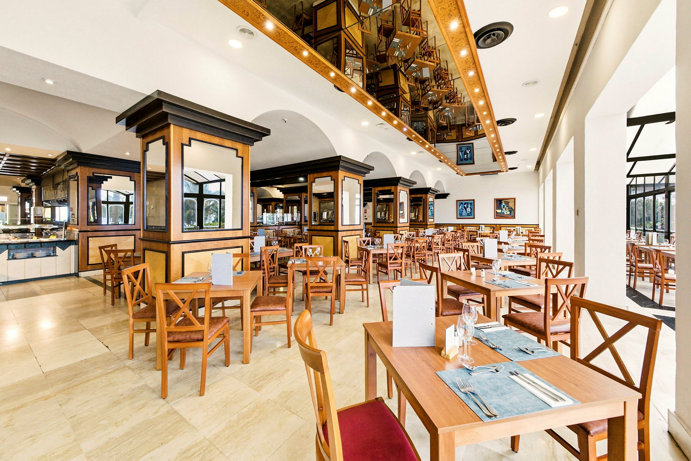 Et rummeligt og veloplyst restaurantområde med træinteriør og flere opstillede borde og stole. (AI-genereret tekst)