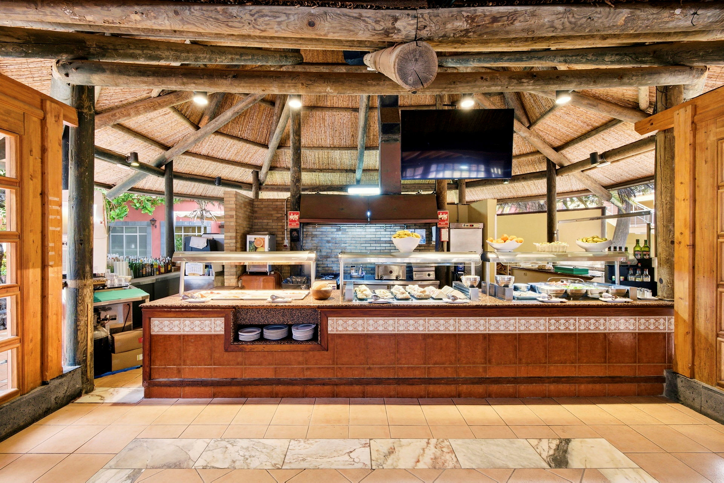 En buffetrestaurant med forskellige madretter og dekorationer under et loft med træbjælker. (AI-genereret tekst)