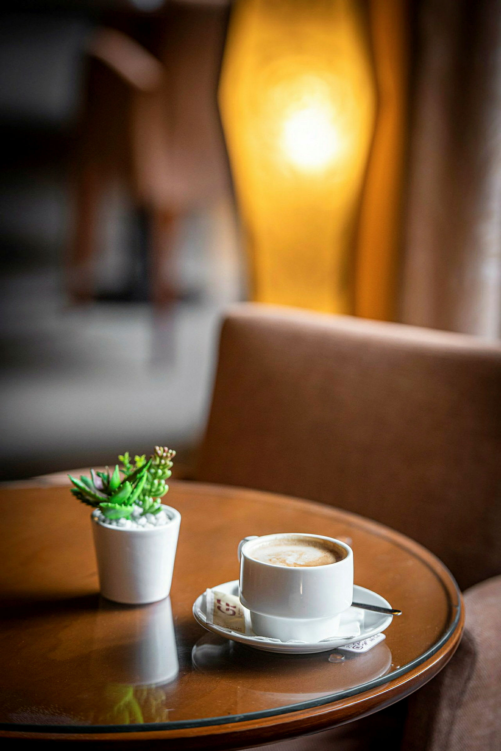 En kop kaffe og en lille potteplante på et rundt bord. (AI-genereret tekst)