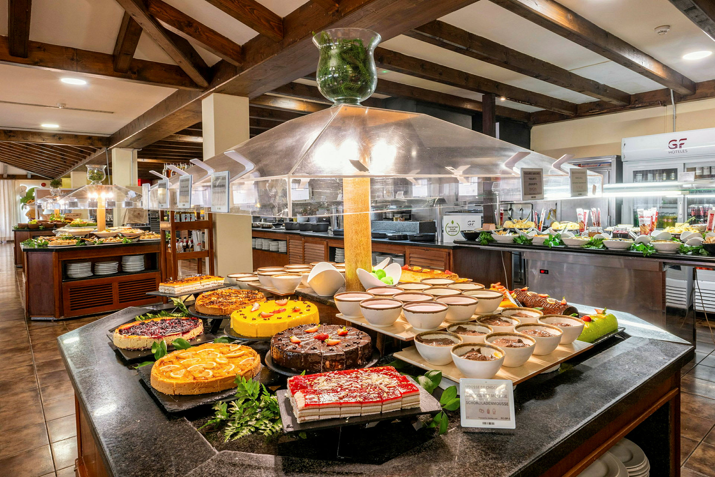 En buffet med forskellige desserter og mad, arrangeret på et bord med skilte. (AI-genereret tekst)
