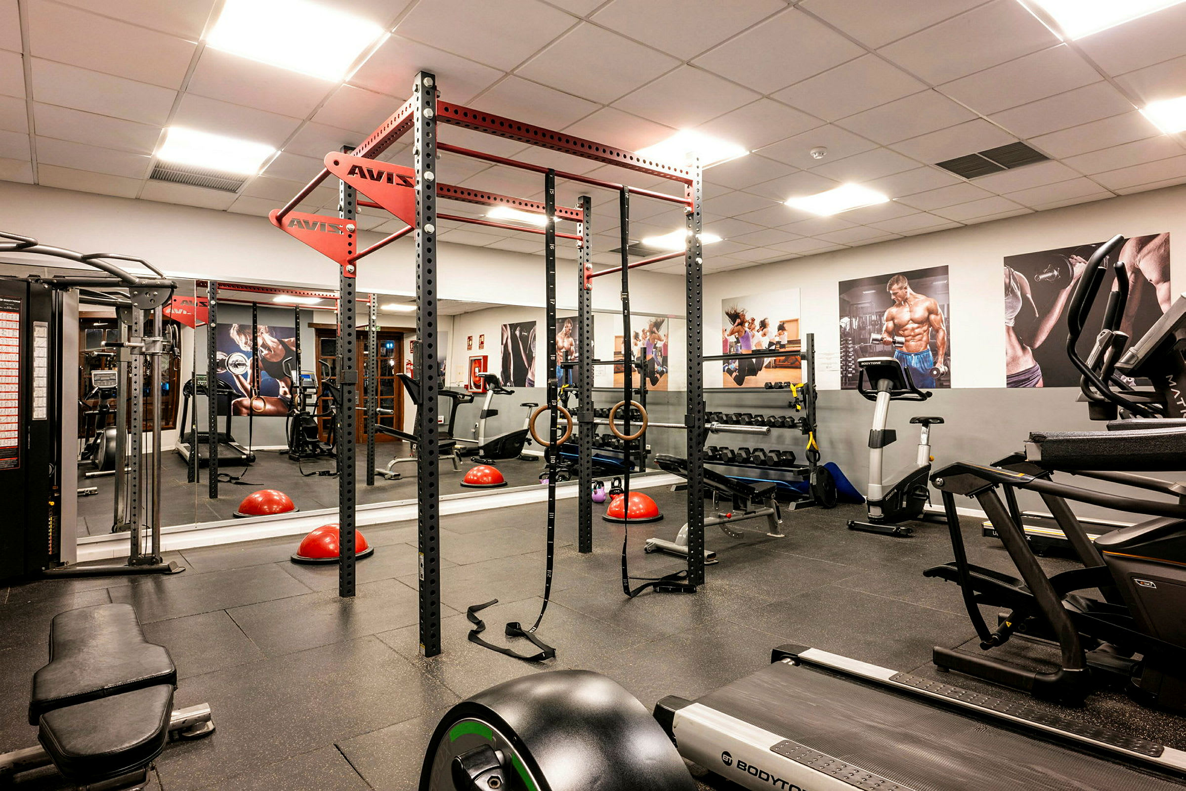 Et fitnesscenter med træningsudstyr såsom løbebånd, vægtsæt og styrketræningsramme. (AI-genereret tekst)