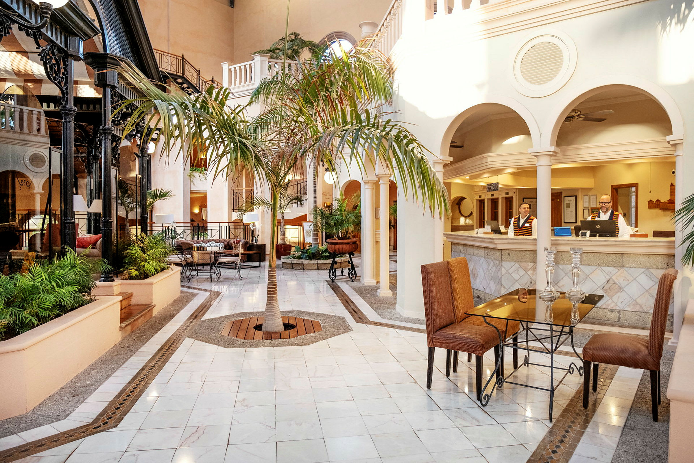 Hotellets lobby med marmorgulv, siddeområder og en central palme. (AI-genereret tekst)