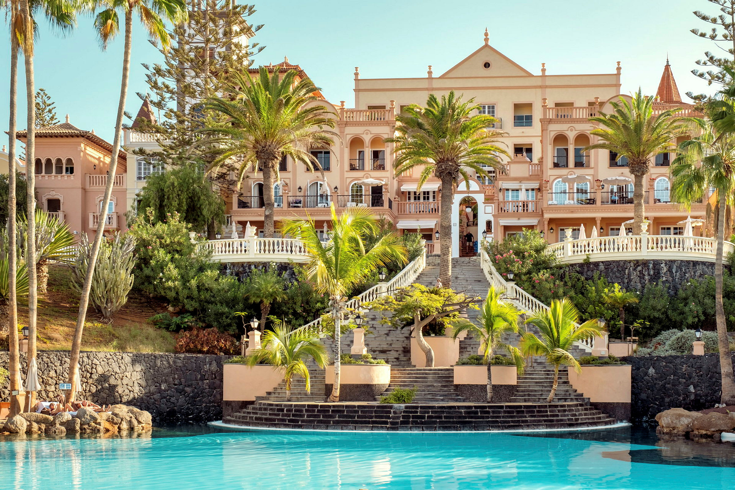 Billede af et hotel med palmer og swimmingpool. (AI-genereret tekst)