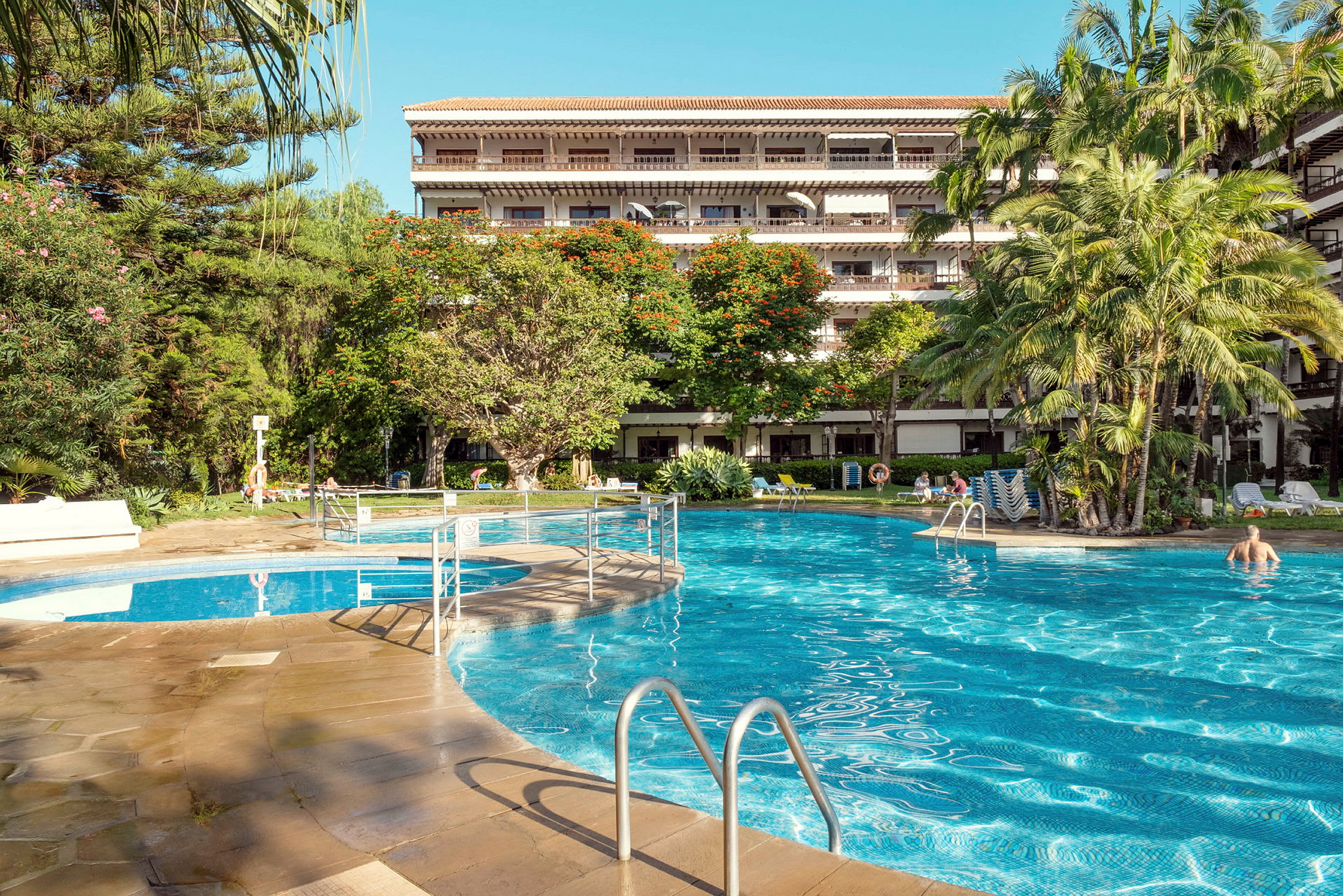 Udendørs pool ved hotel omgivet af grønt. (AI-genereret tekst)