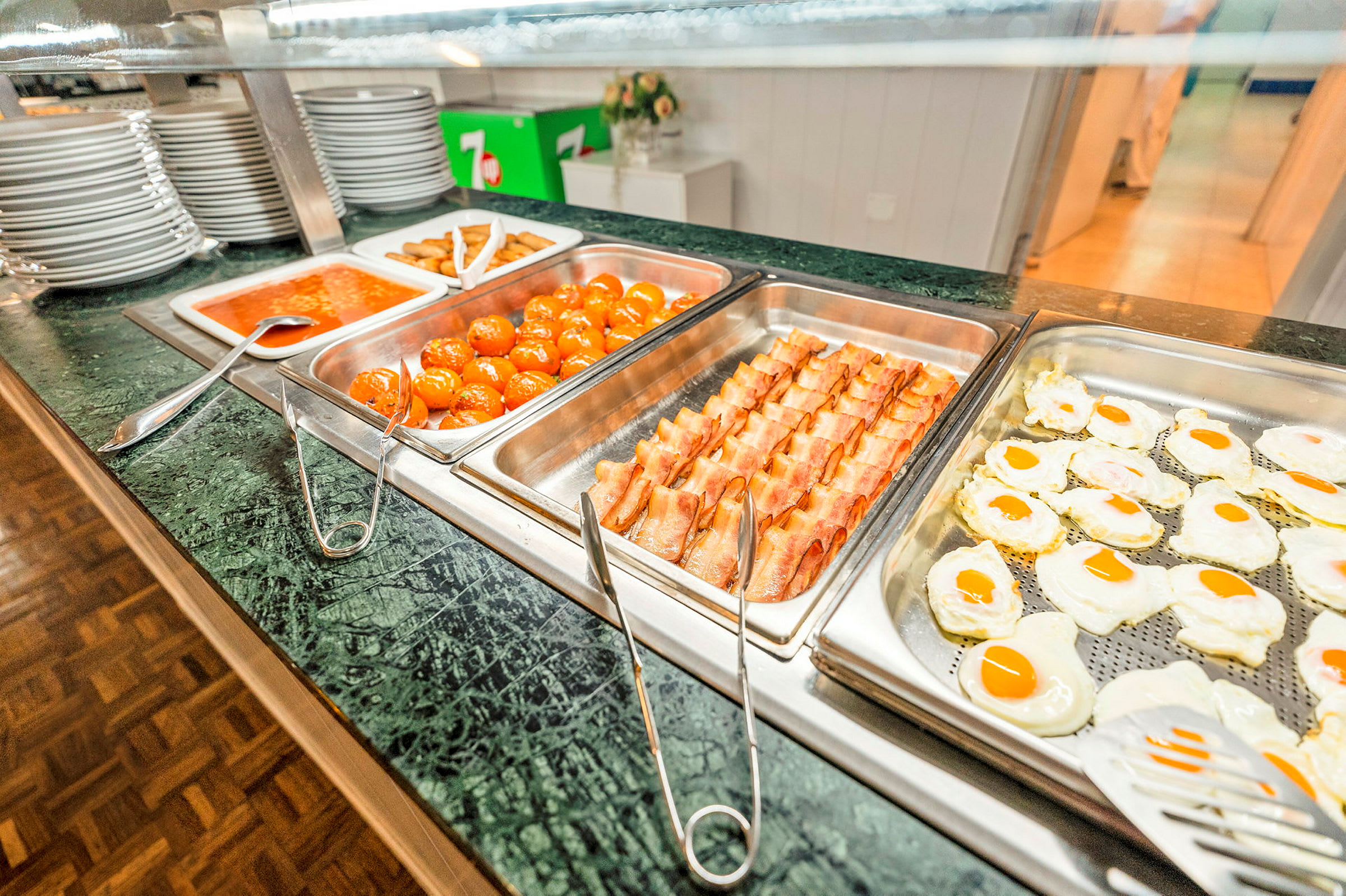 Buffetservering med forskellige retter, herunder spejlæg, bacon, kødboller og tomatsauce. (AI-genereret tekst)