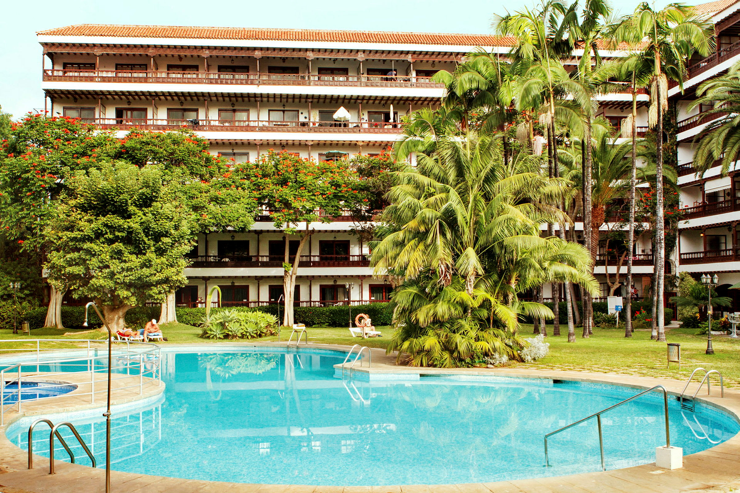 Hotel med frodig have og pool. (AI-genereret tekst)