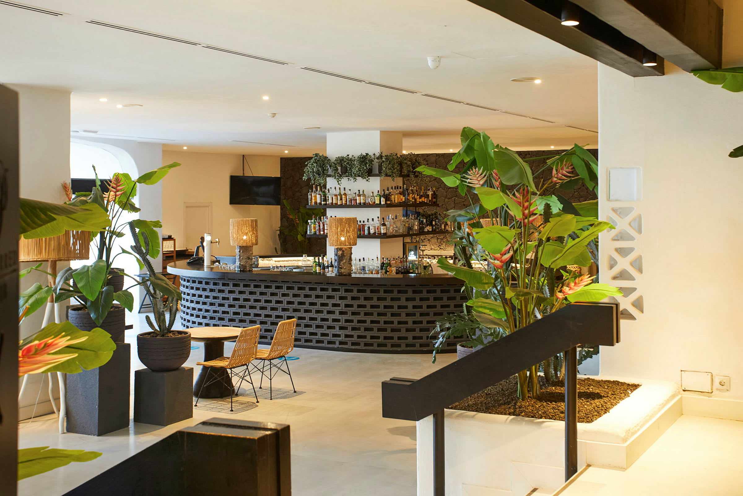En hotelbar med planteudsmykning, siddepladser og oplyst interiør. (AI-genereret tekst)