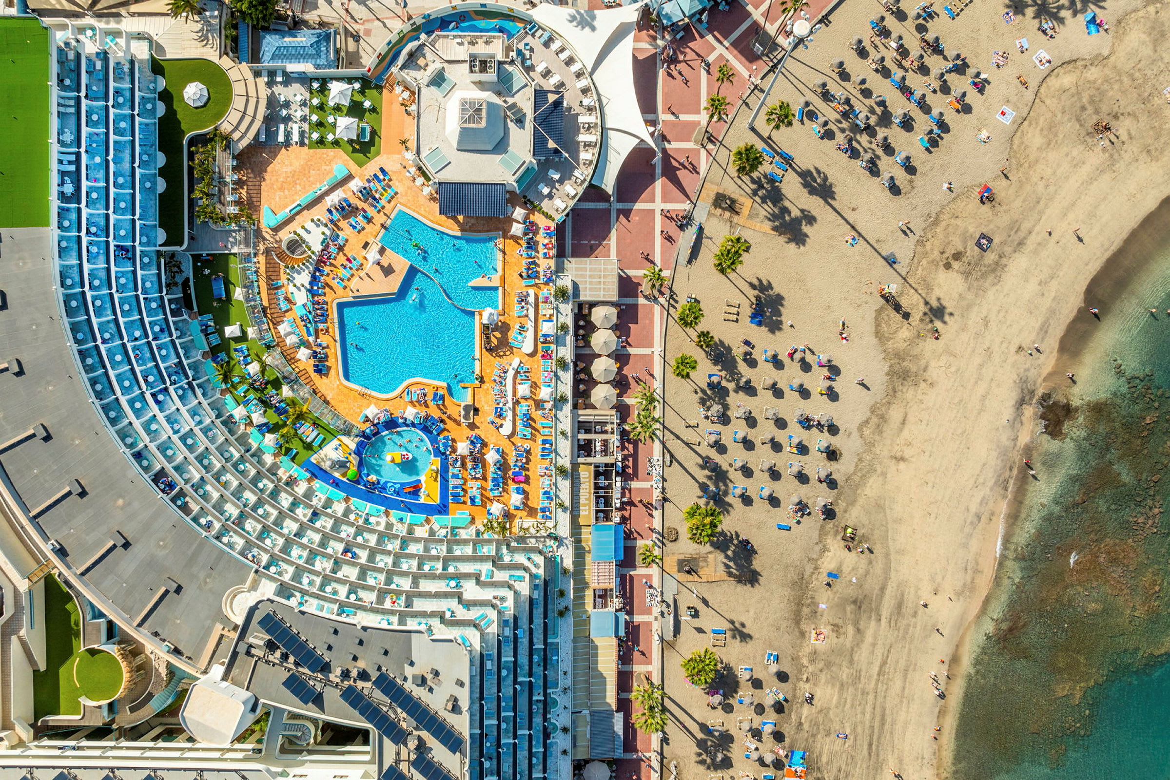 Luftfoto af hotelområde med pool og strand. (AI-genereret tekst)