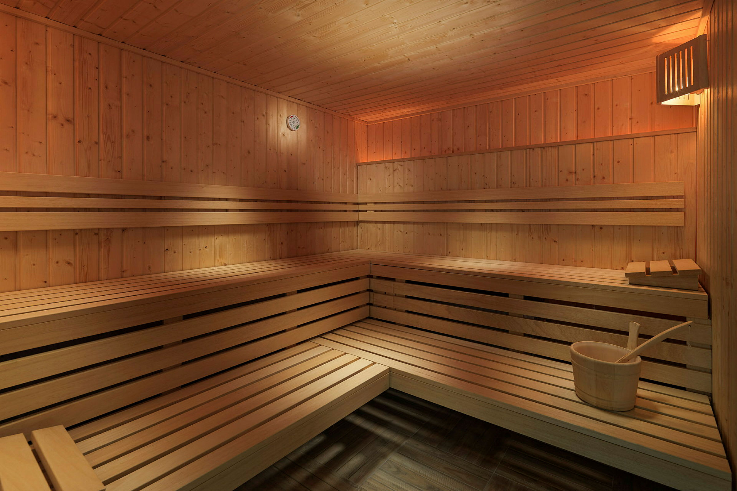 Interiør af en sauna med træpaneler og bænke. (AI-genereret tekst)